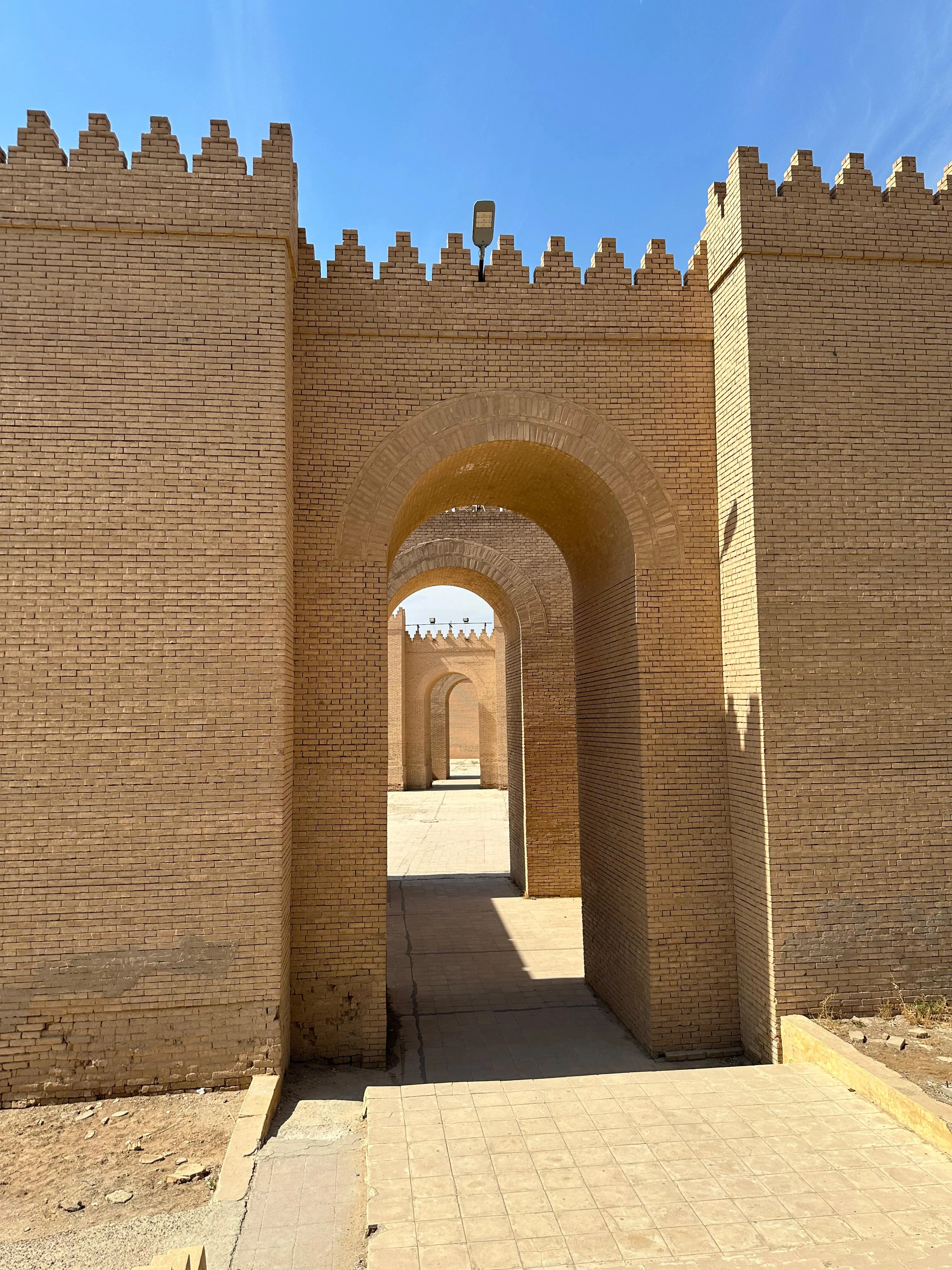 Babylon city wall reconstruction in Iraq with sandy bricks and arched entryways under sunlight