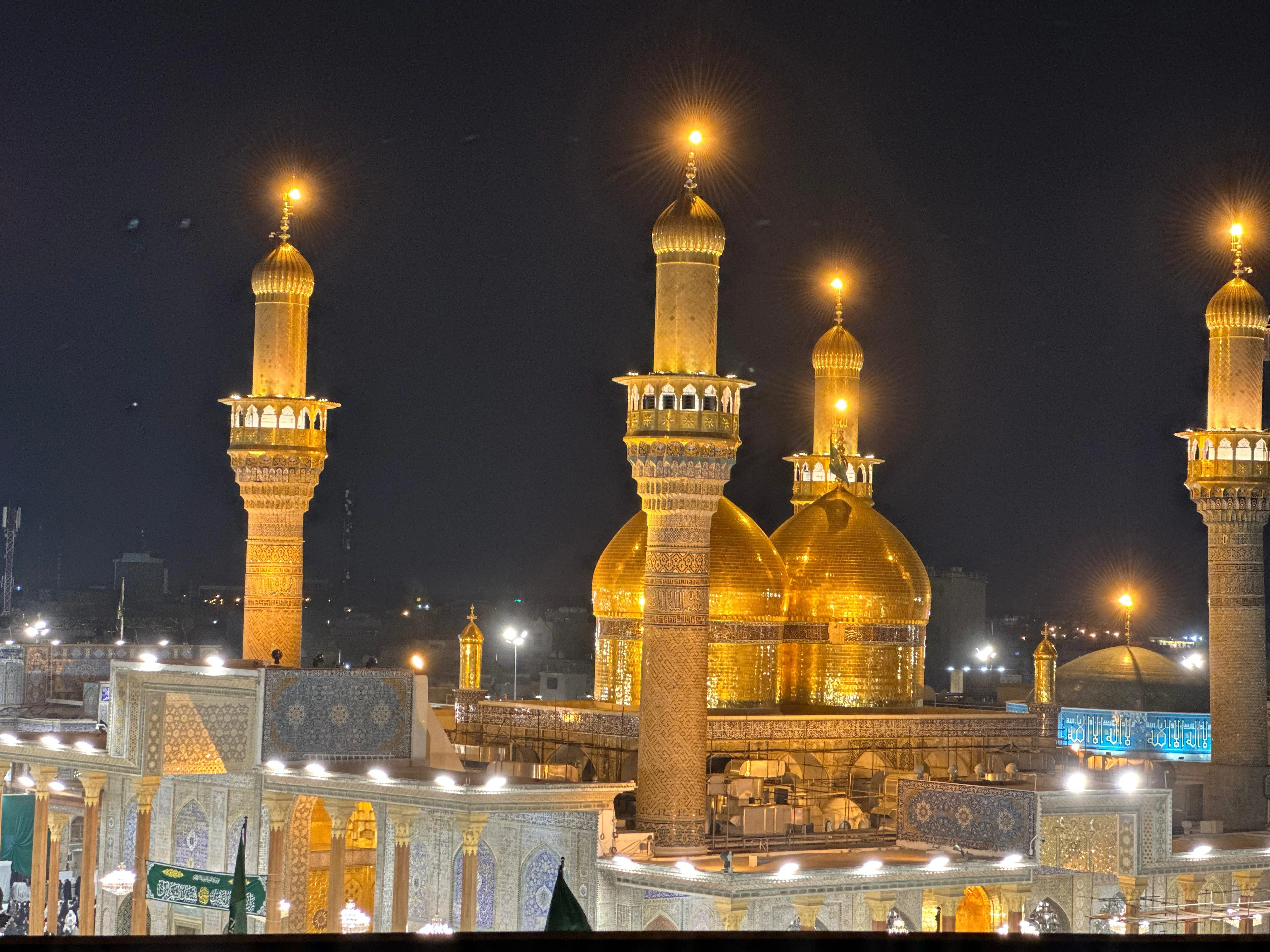 Illuminated golden domes of Al-Kadhimiya Shrine in Baghdad, Iraq shining against the night sky