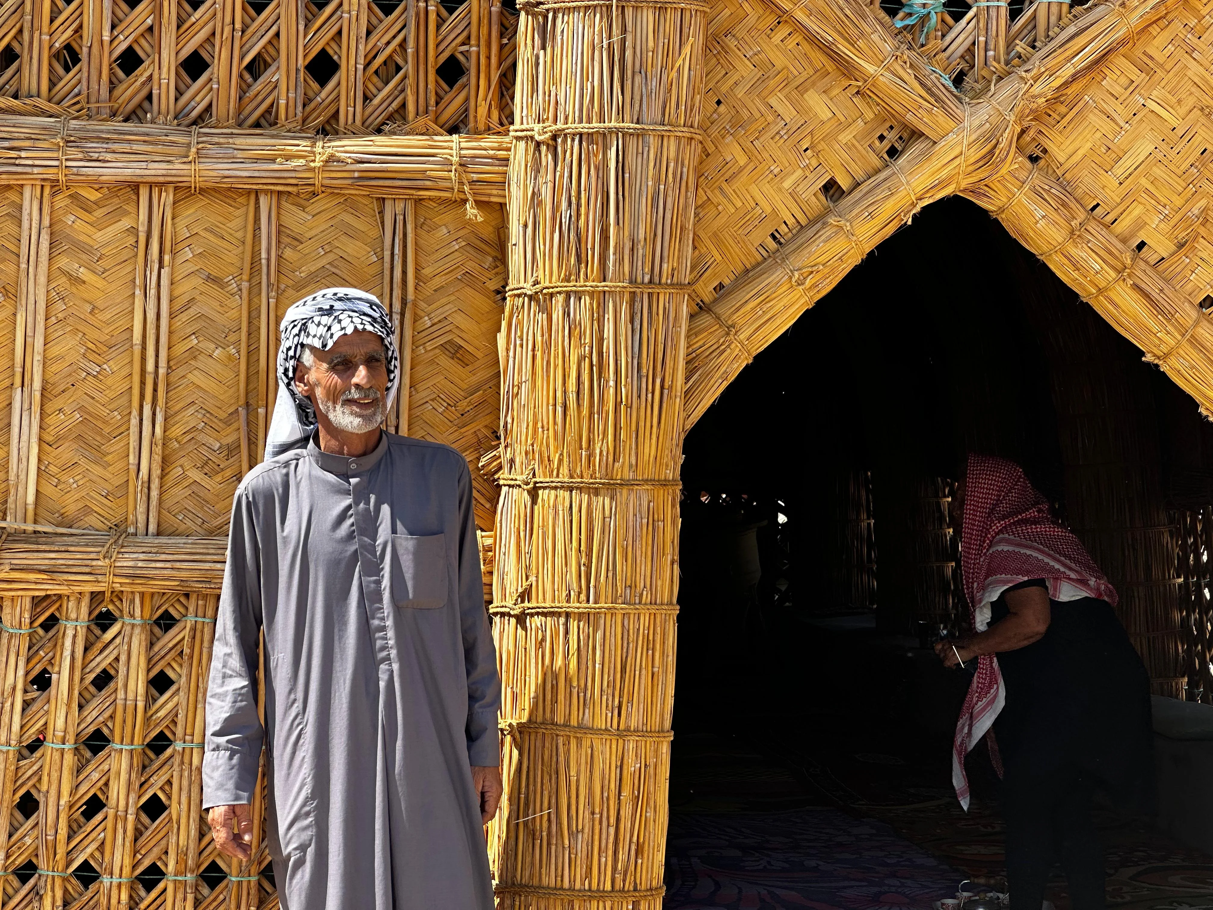 Elderly Marsh Arab man in traditional clothing outside a reed house in southern Iraq’s marshes