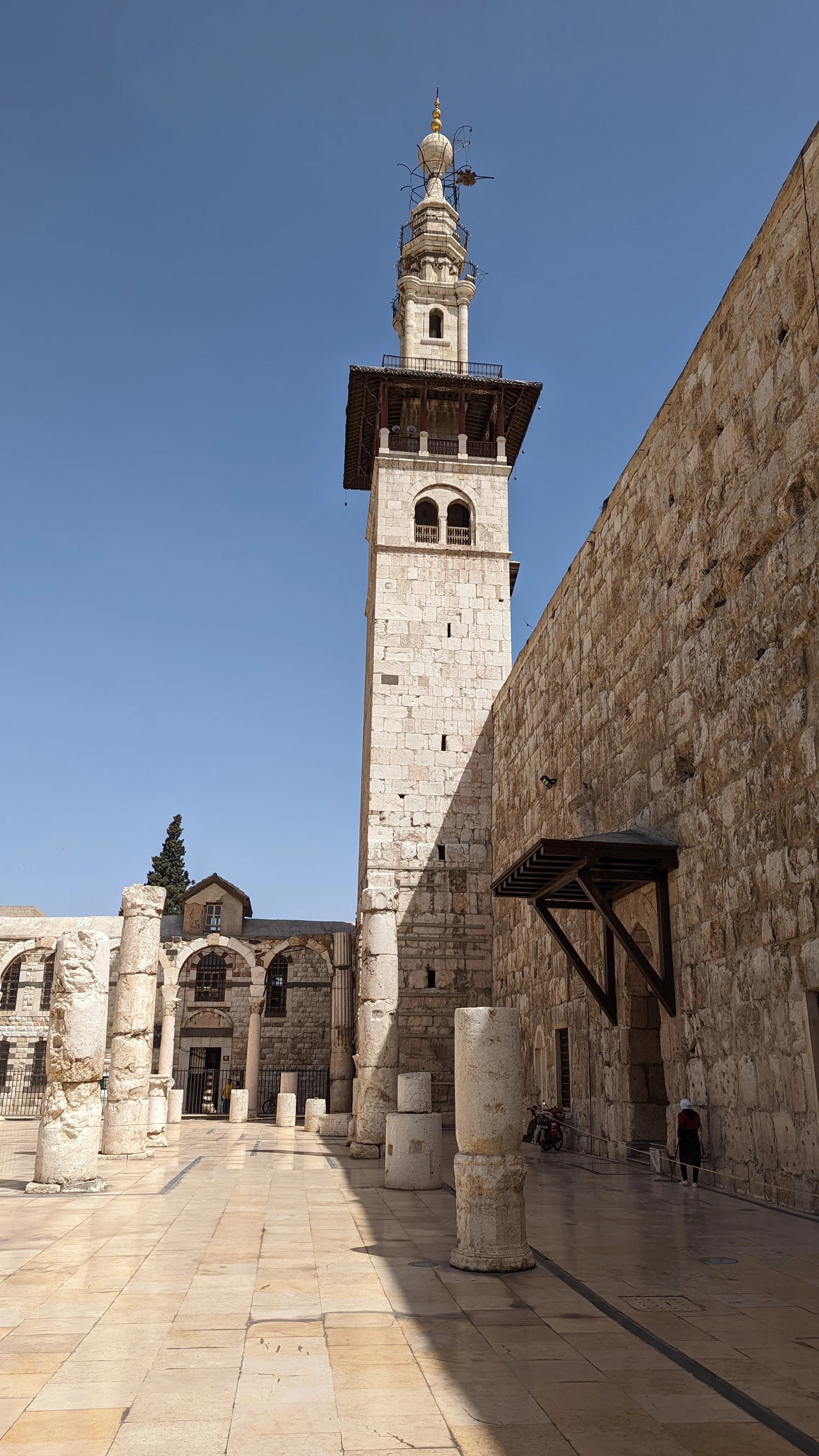 Minaret of the Umayyad Mosque in Damascus framed by ancient Roman columns and stone walls