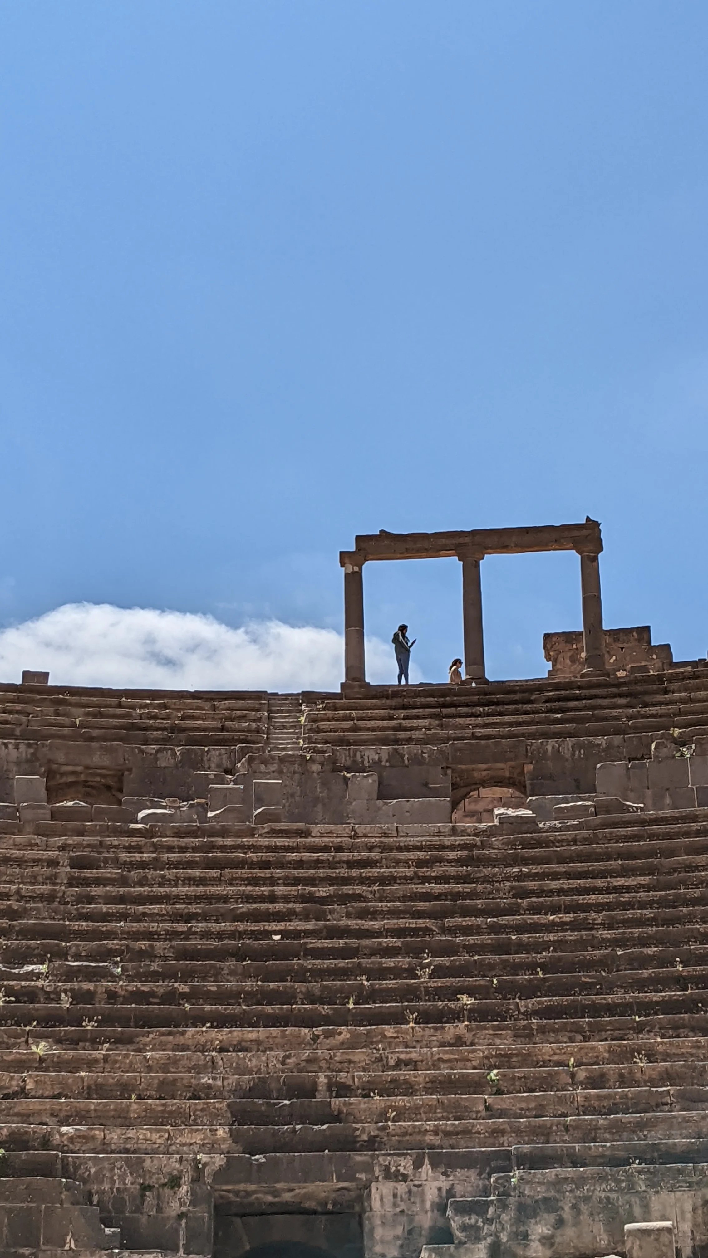 Upper view of Bosra amphitheater showing visitors among towering Roman ruins and stone steps