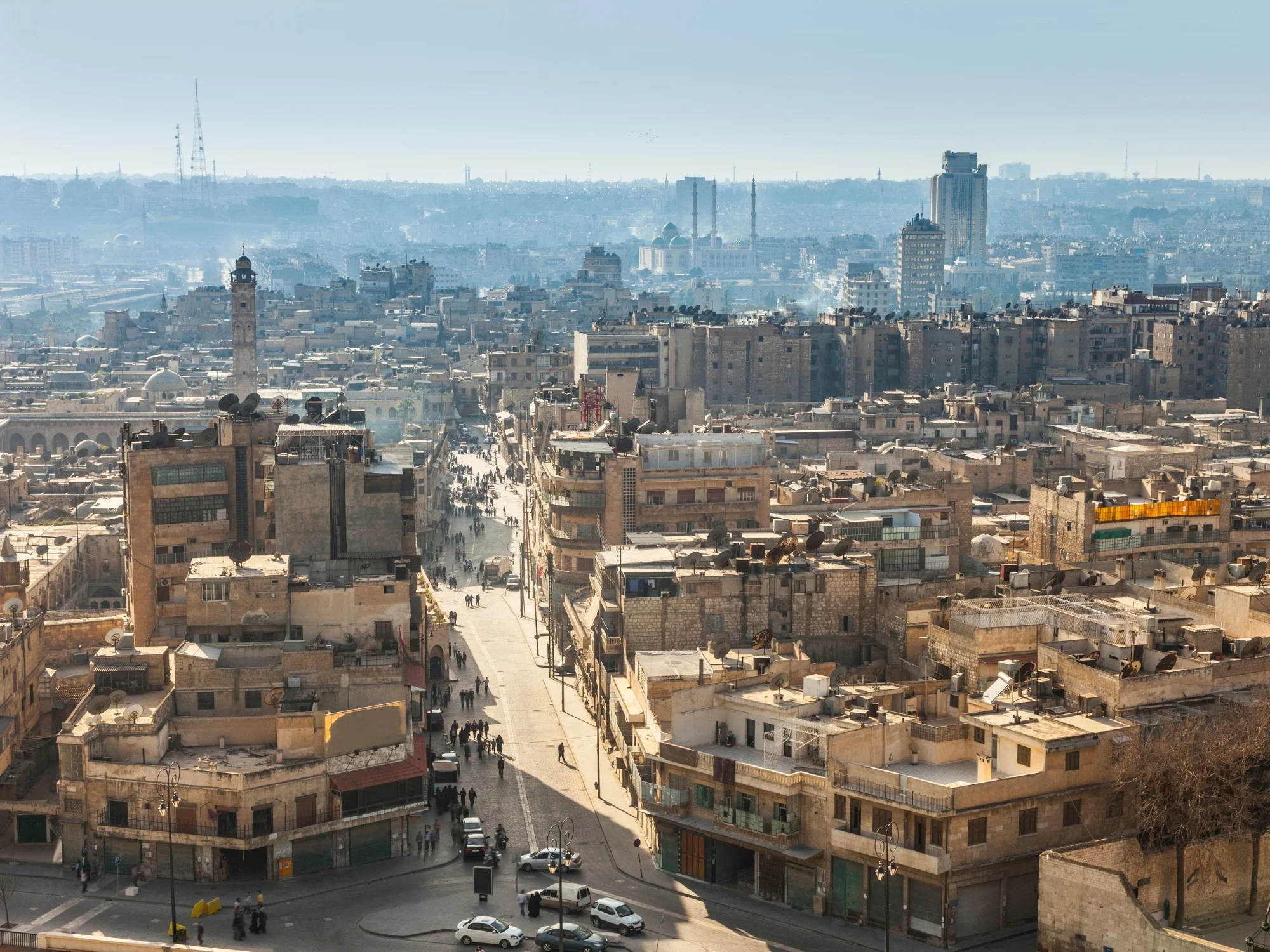 Panoramic view of Aleppo cityscape with minarets, residential rooftops, and distant skyline