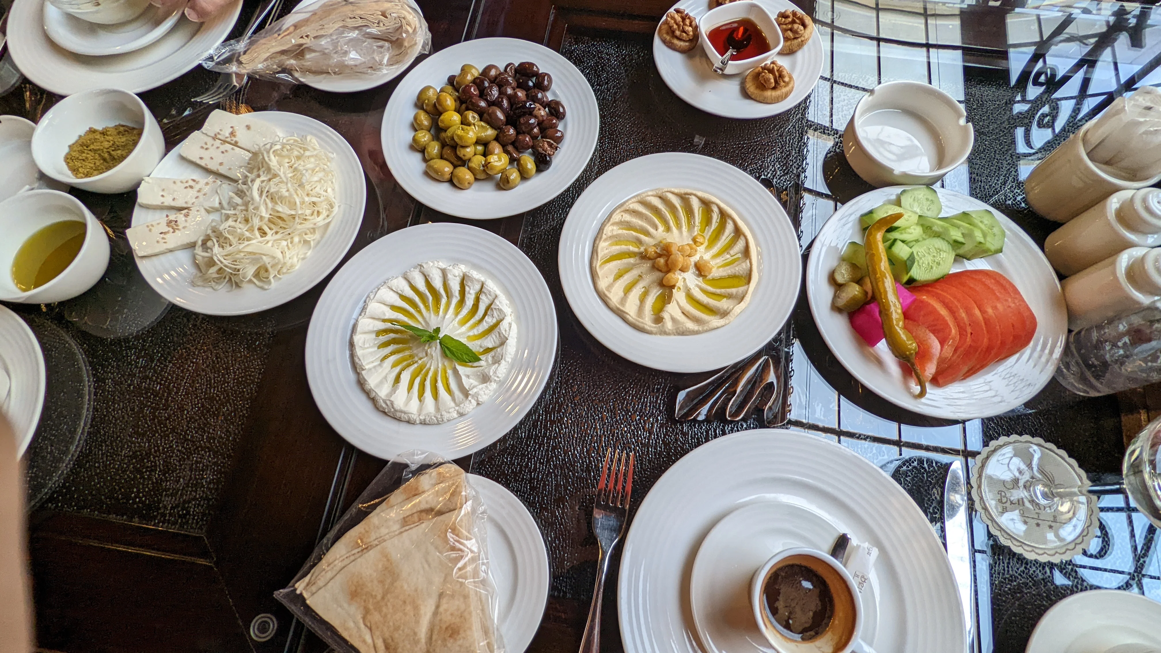 Middle Eastern breakfast spread with hummus, labneh, olives, fresh vegetables, bread, and coffee