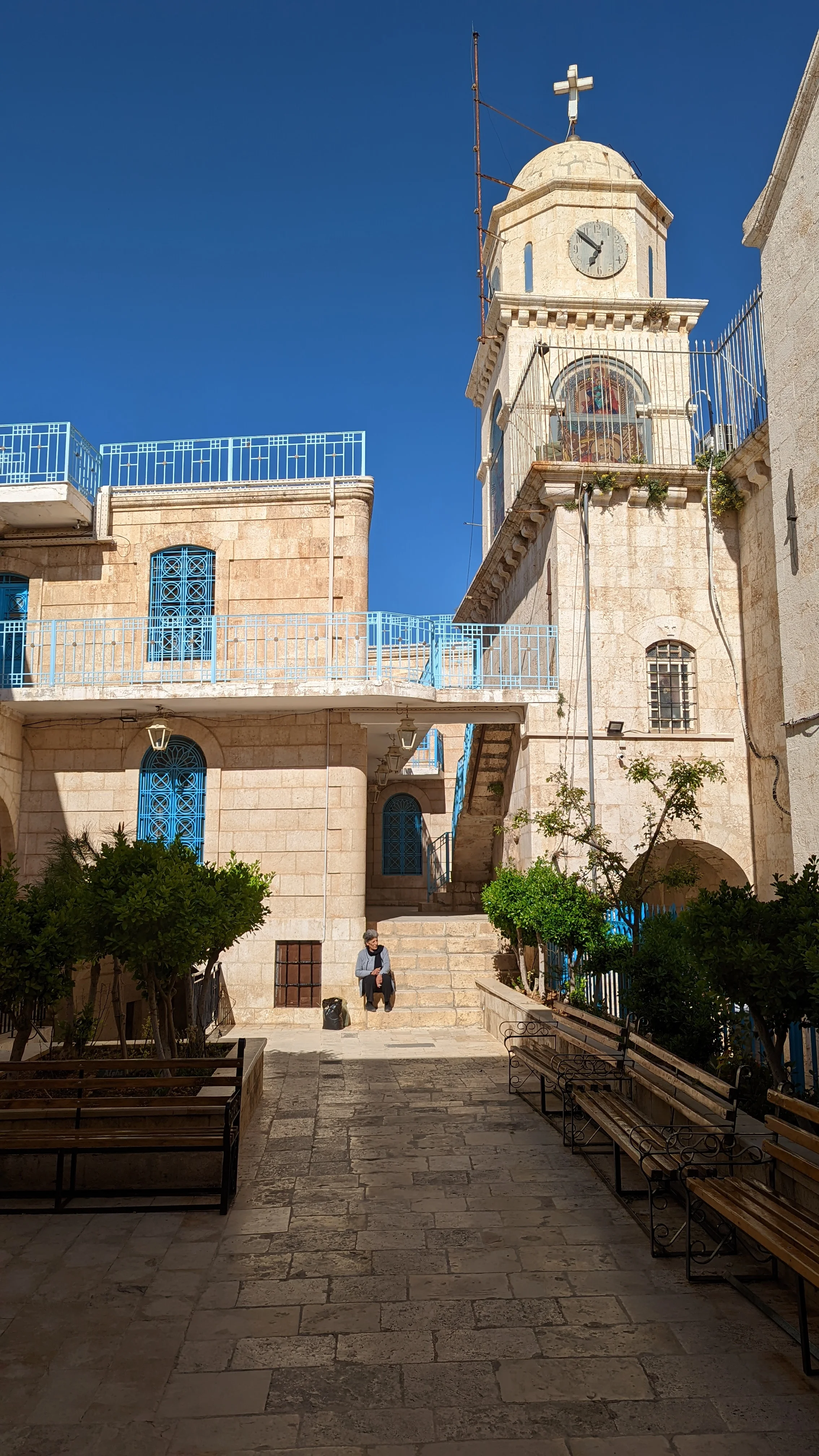 Courtyard of a Christian monastery in Maaloula with blue railings, benches, and stone pathways