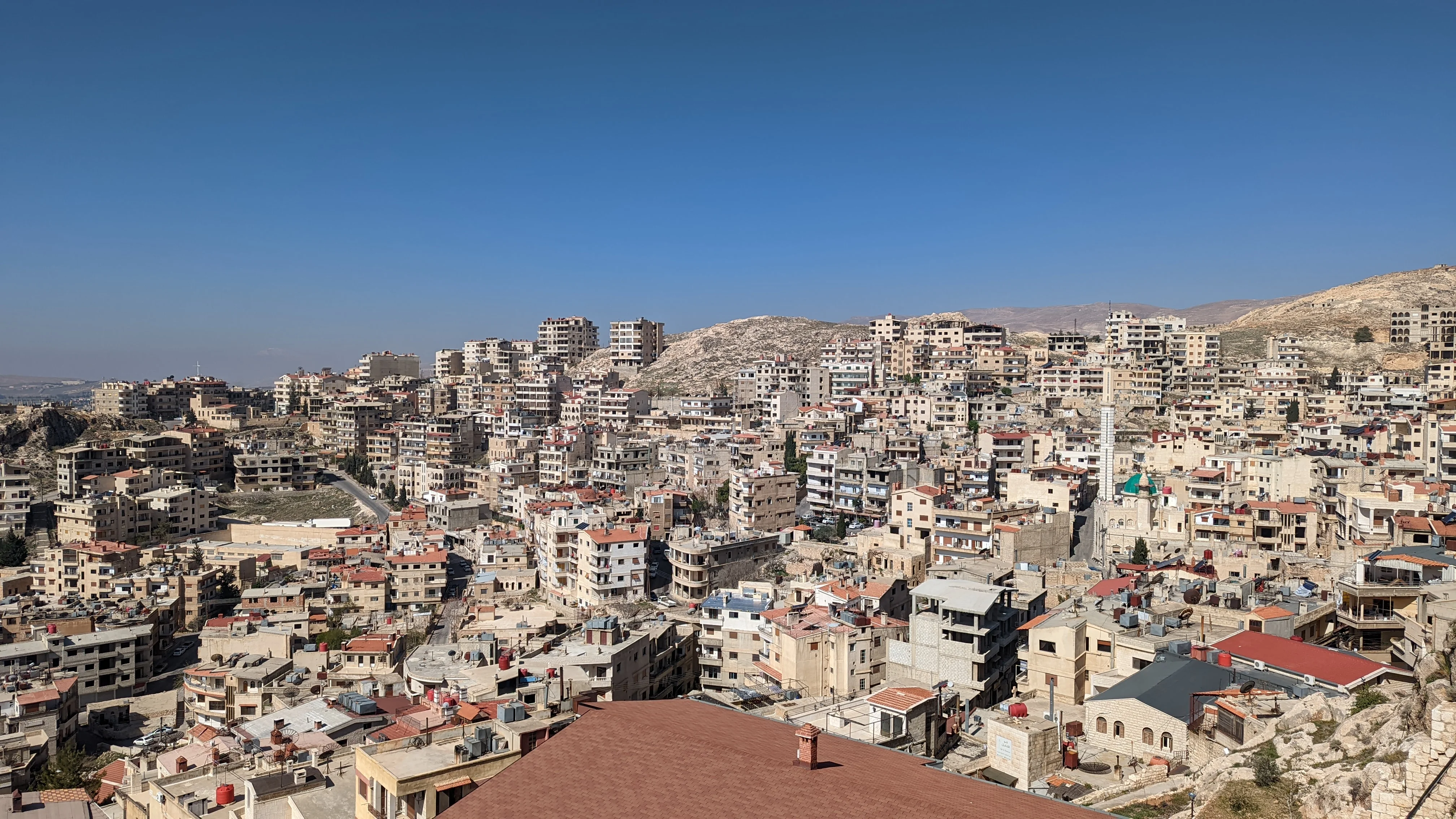 Panoramic view of Maaloula village with dense beige buildings nestled in a mountainous area
