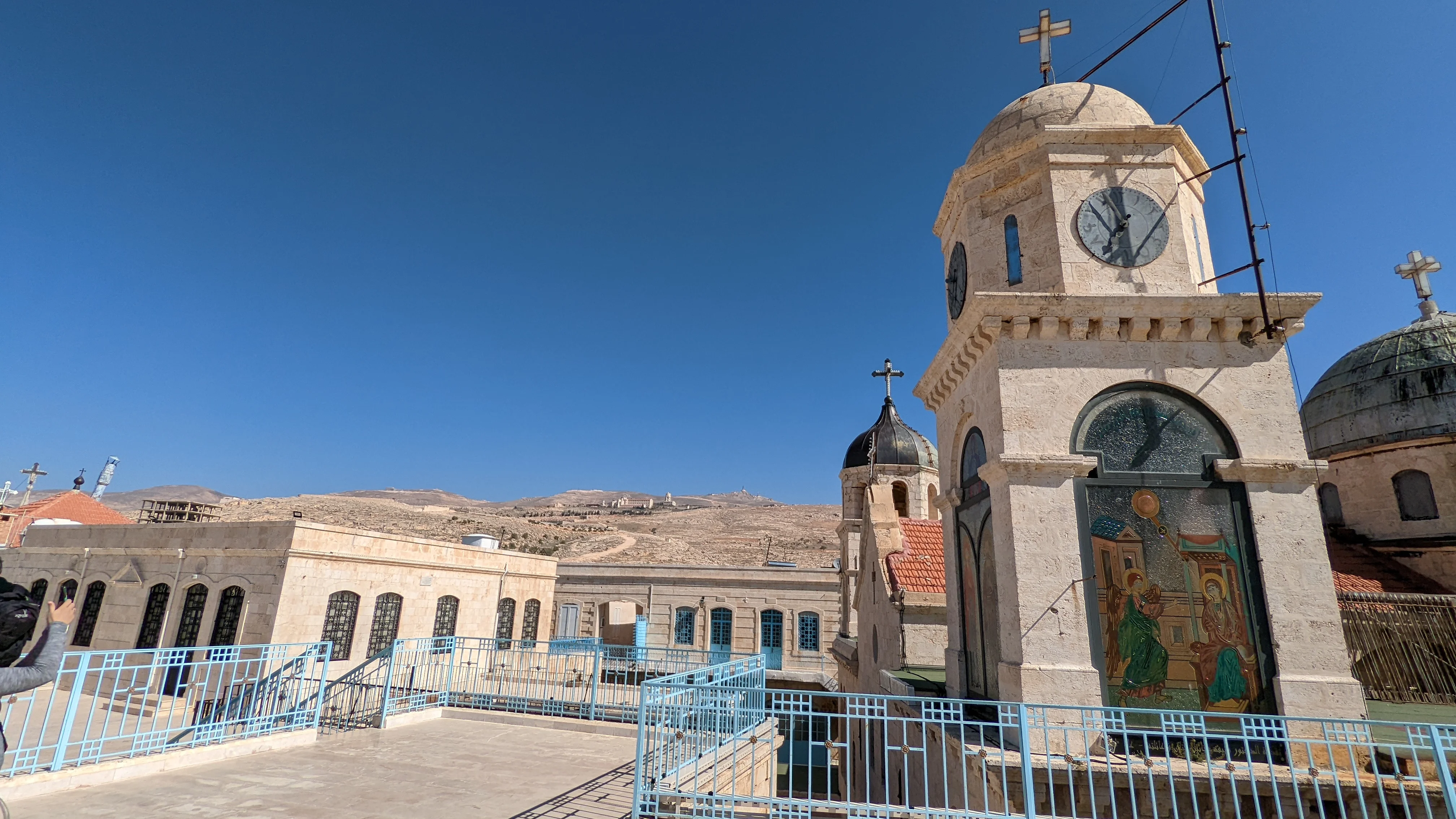 Rooftop view of Maaloula monastery with bell tower, domes, and distant mountain terrain
