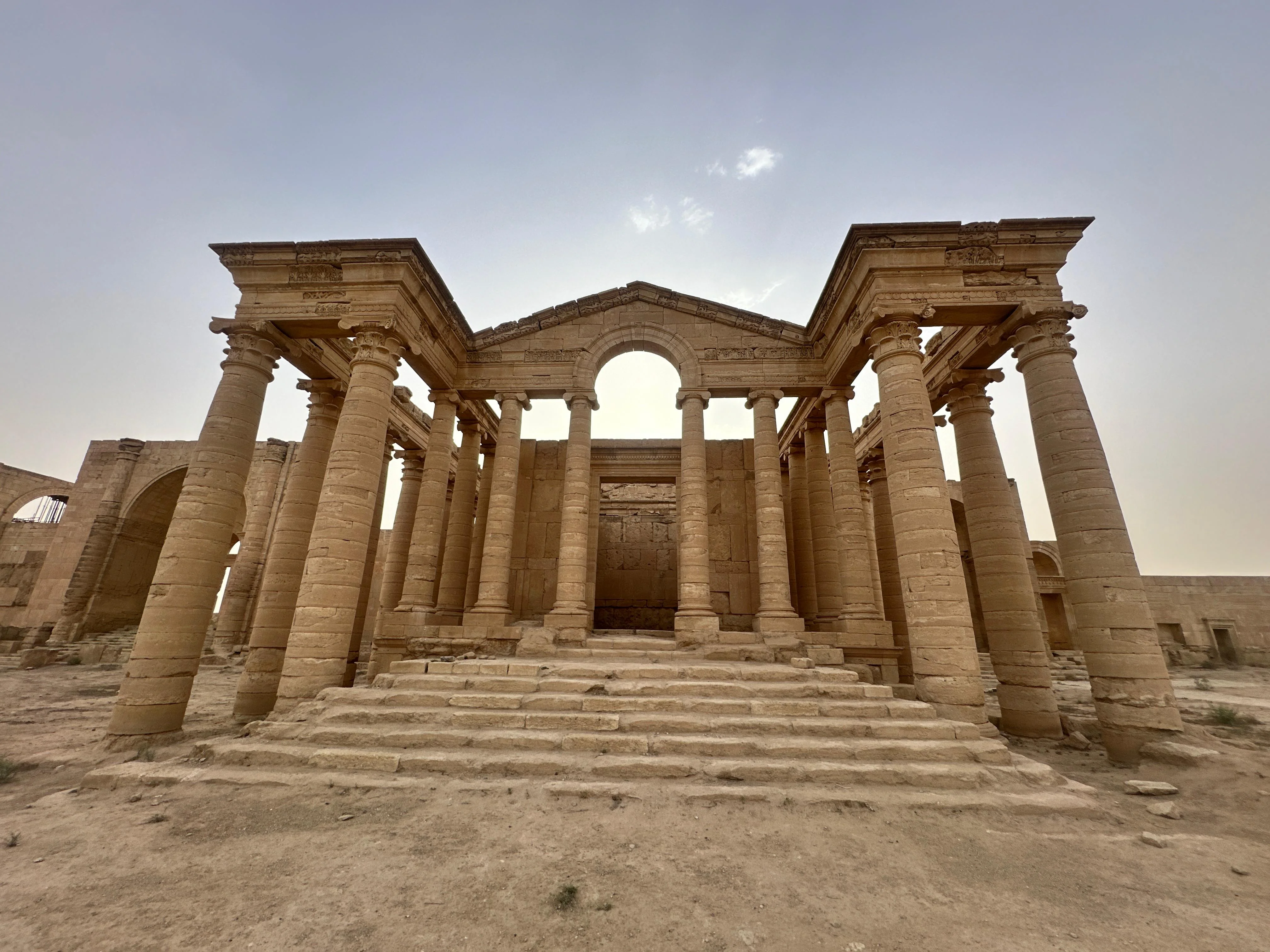 Ruins of Hatra temple in Iraq with Greco-Roman columns under a hazy sky in the desert