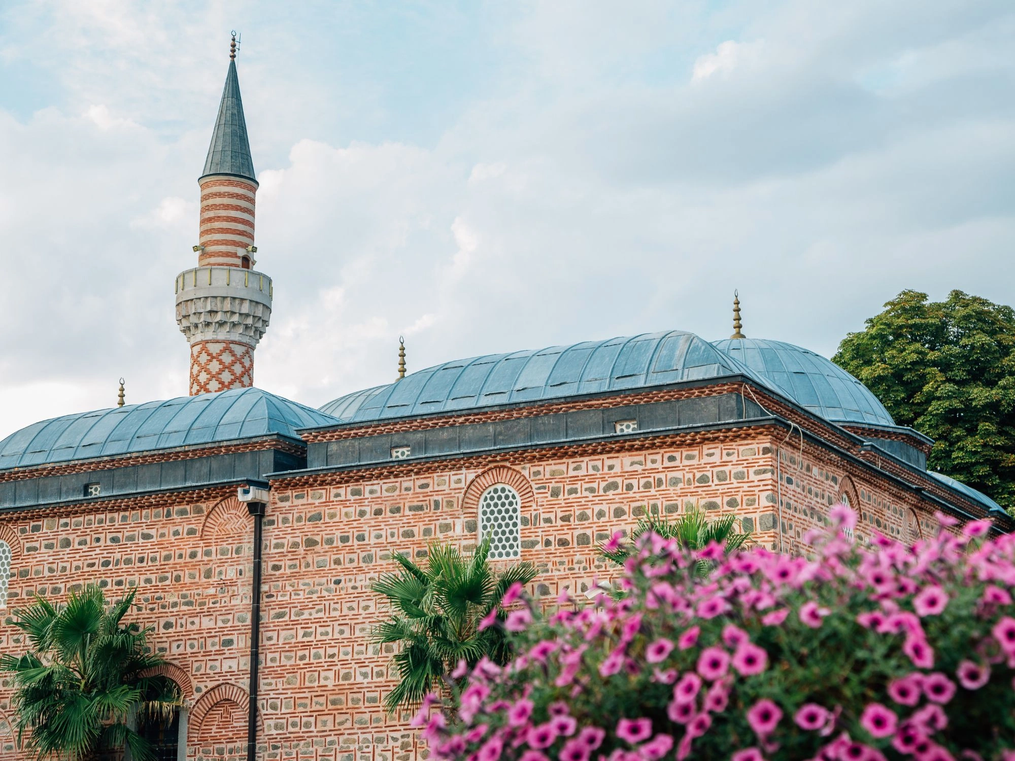 Dzhumaya Mosque in Plovdiv with minaret and pink flowers, Bulgaria cultural landmark.