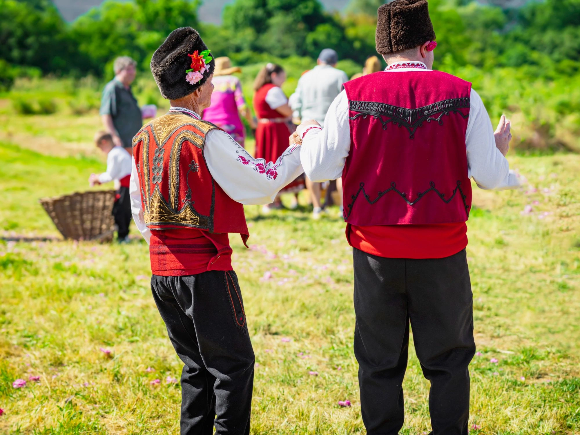 Bulgarian men in traditional folk costumes dancing at a cultural festival outdoors.