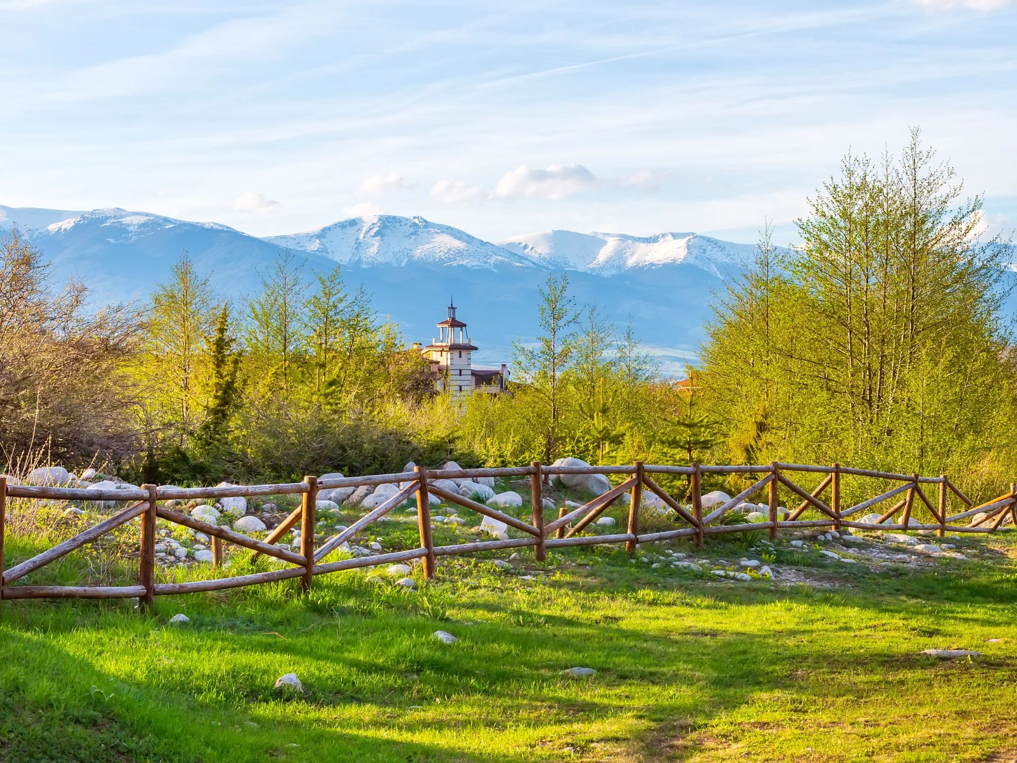 Wooden fence and spring landscape near Bansko with Pirin mountains in Bulgaria.