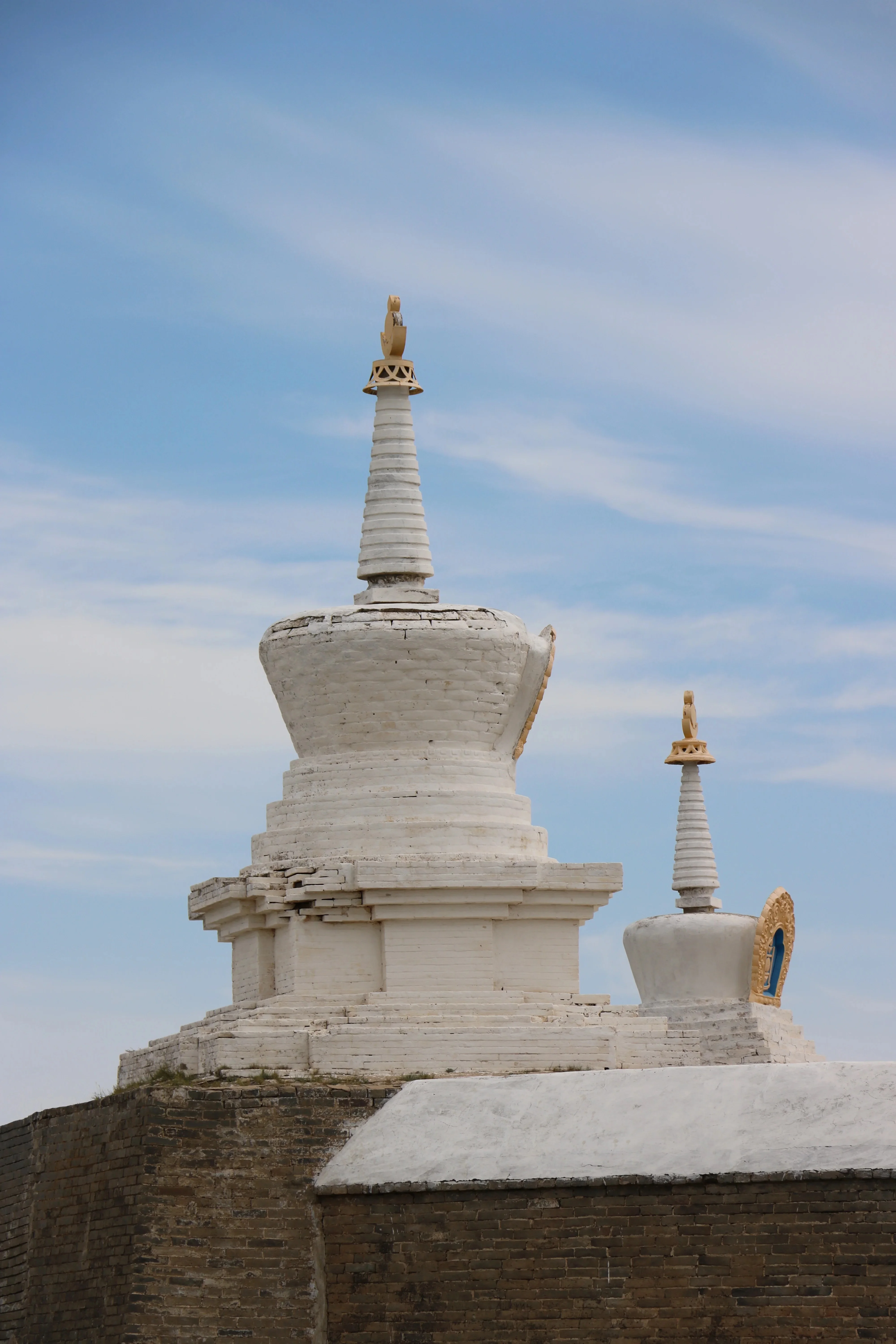 White stupas of Erdene Zuu Monastery rising against blue Mongolian sky.