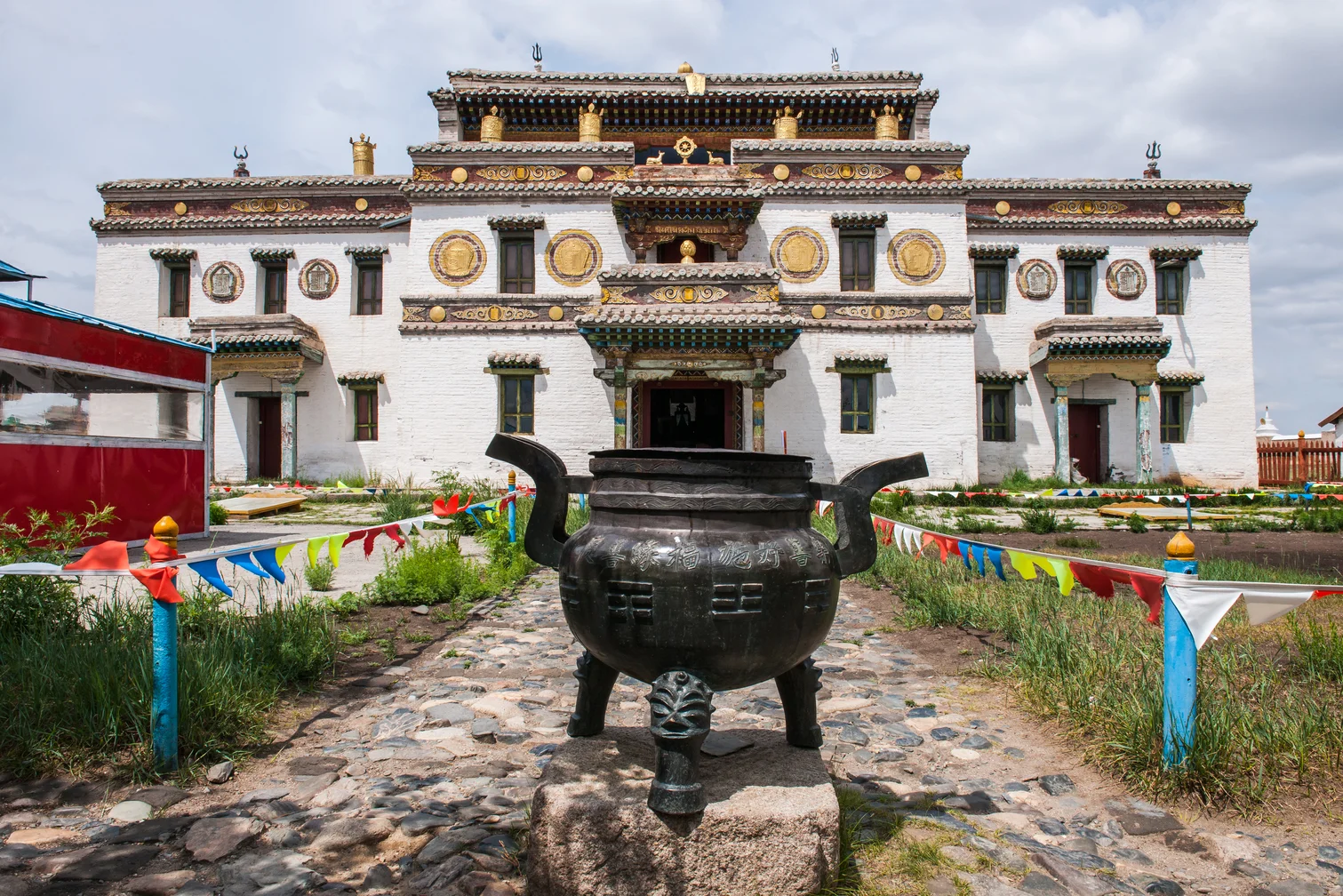 Erdenezuu Monastery Mongolia, ornate white building with bronze incense burner in front.