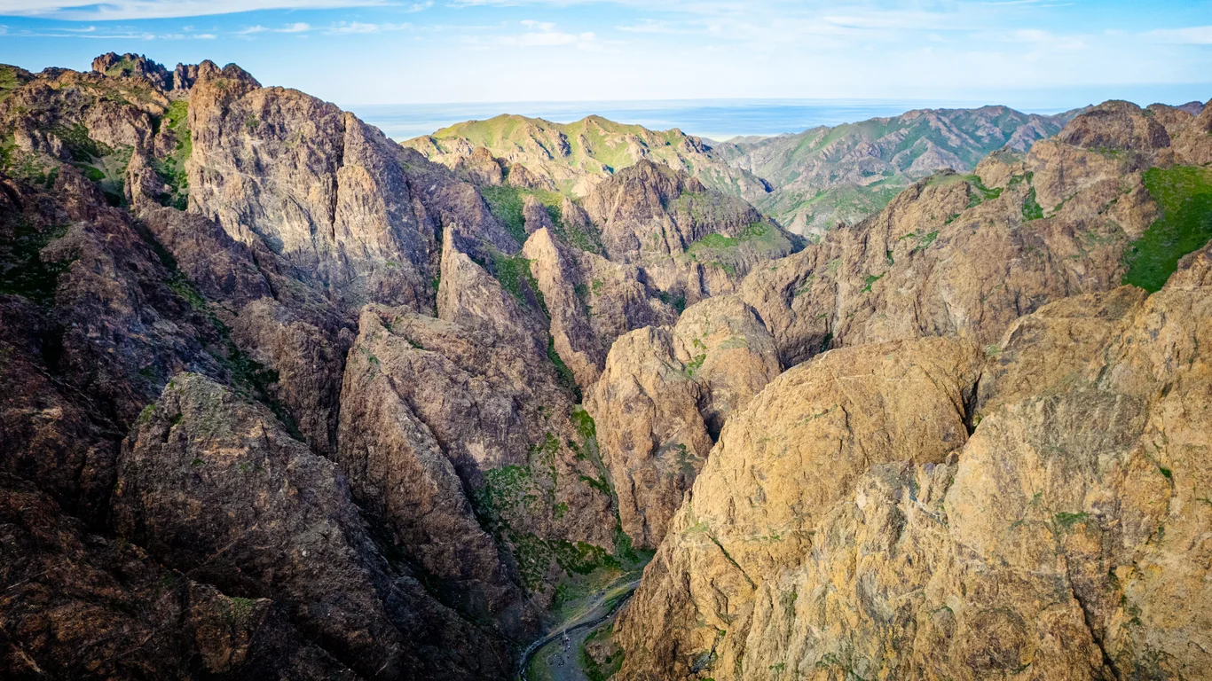 Yolyn Am Mongolia, dramatic rocky cliffs and green slopes seen from above.