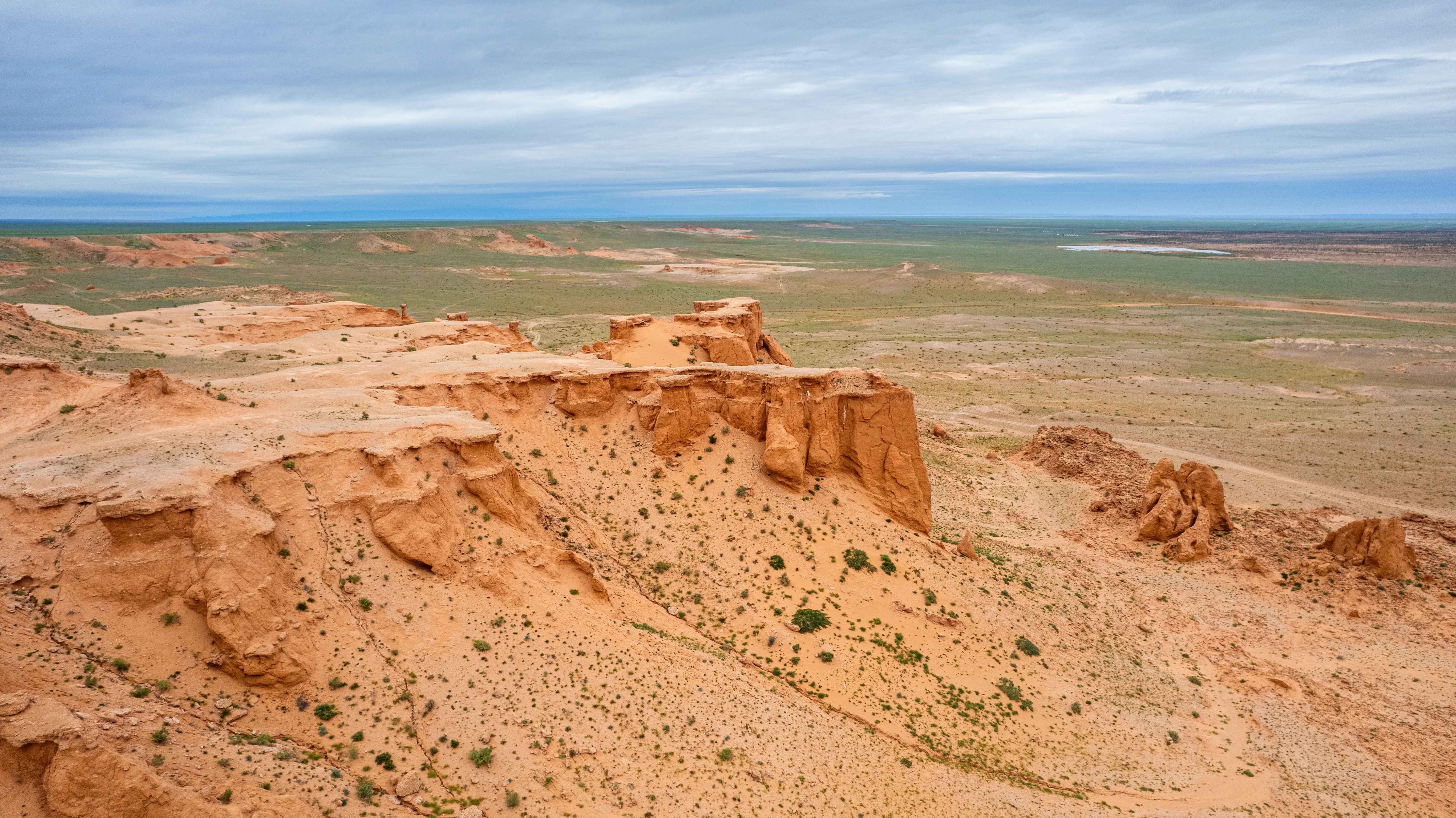Red cliffs of Mongolia's Flaming Cliffs stretch across Gobi Desert plain.