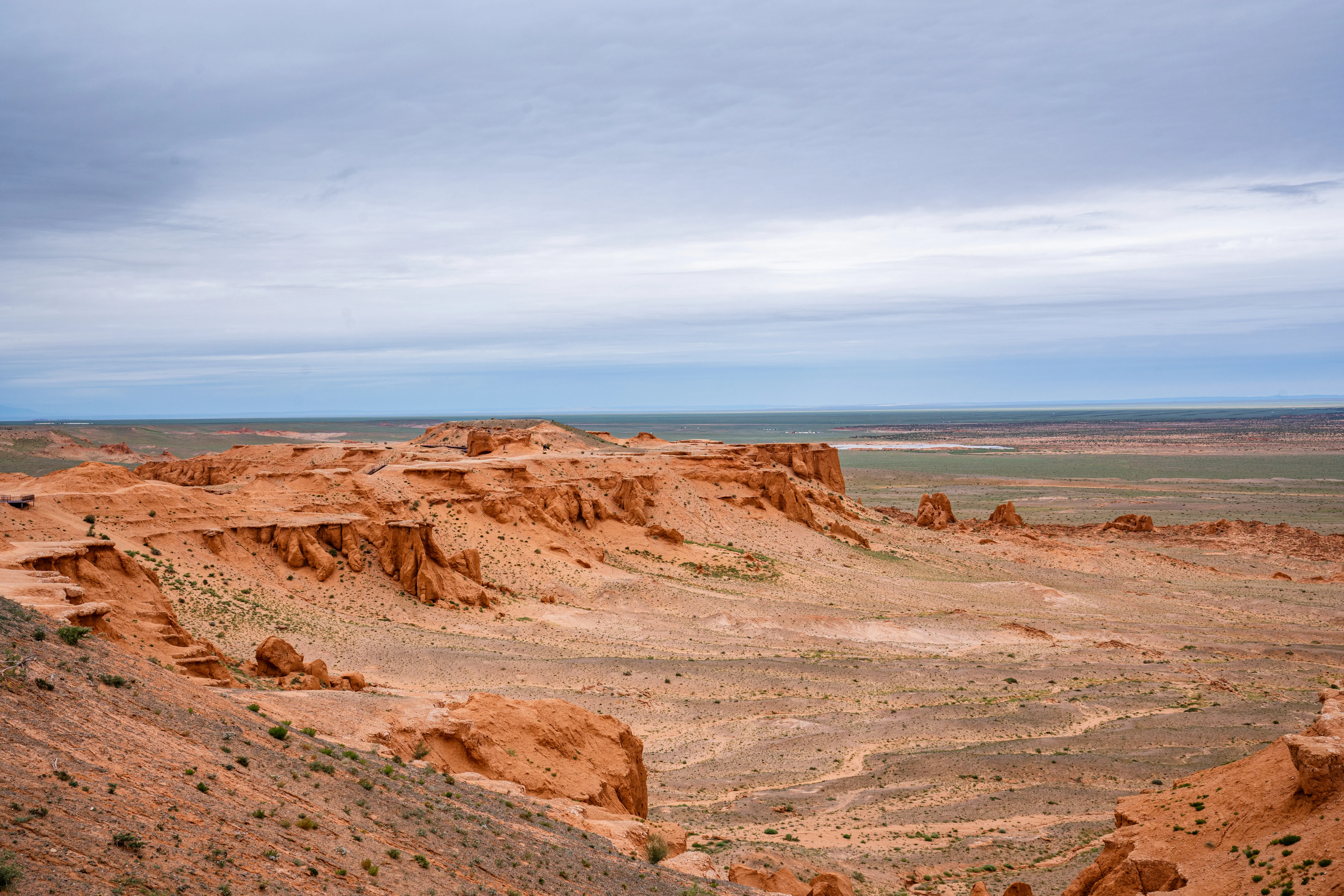 Bayanzag Flaming Cliffs Mongolia red sandstone formations under cloudy sky panoramic view.
