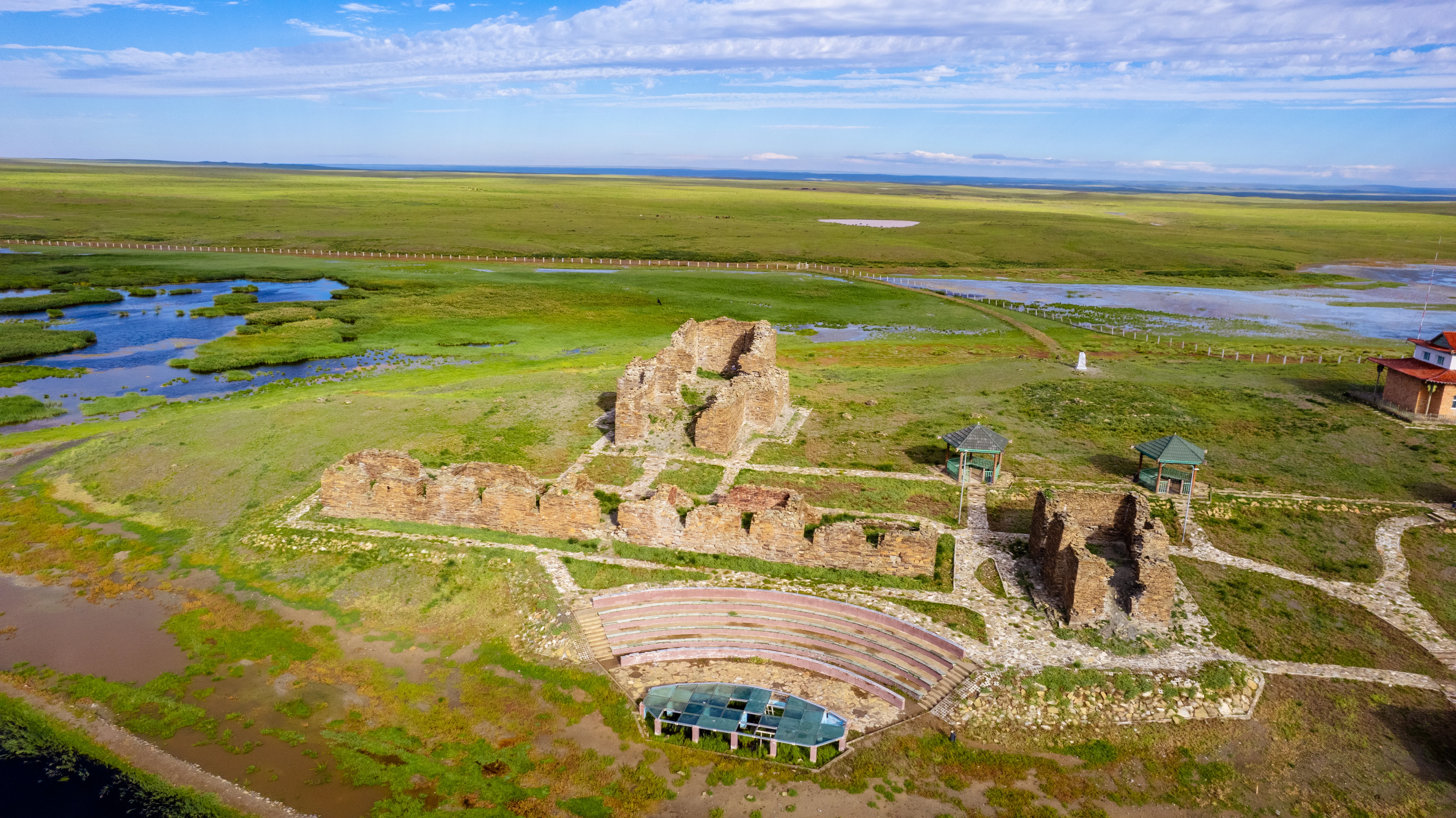 Aerial view of Ongiin Khiid Monastery ruins surrounded by green plains.