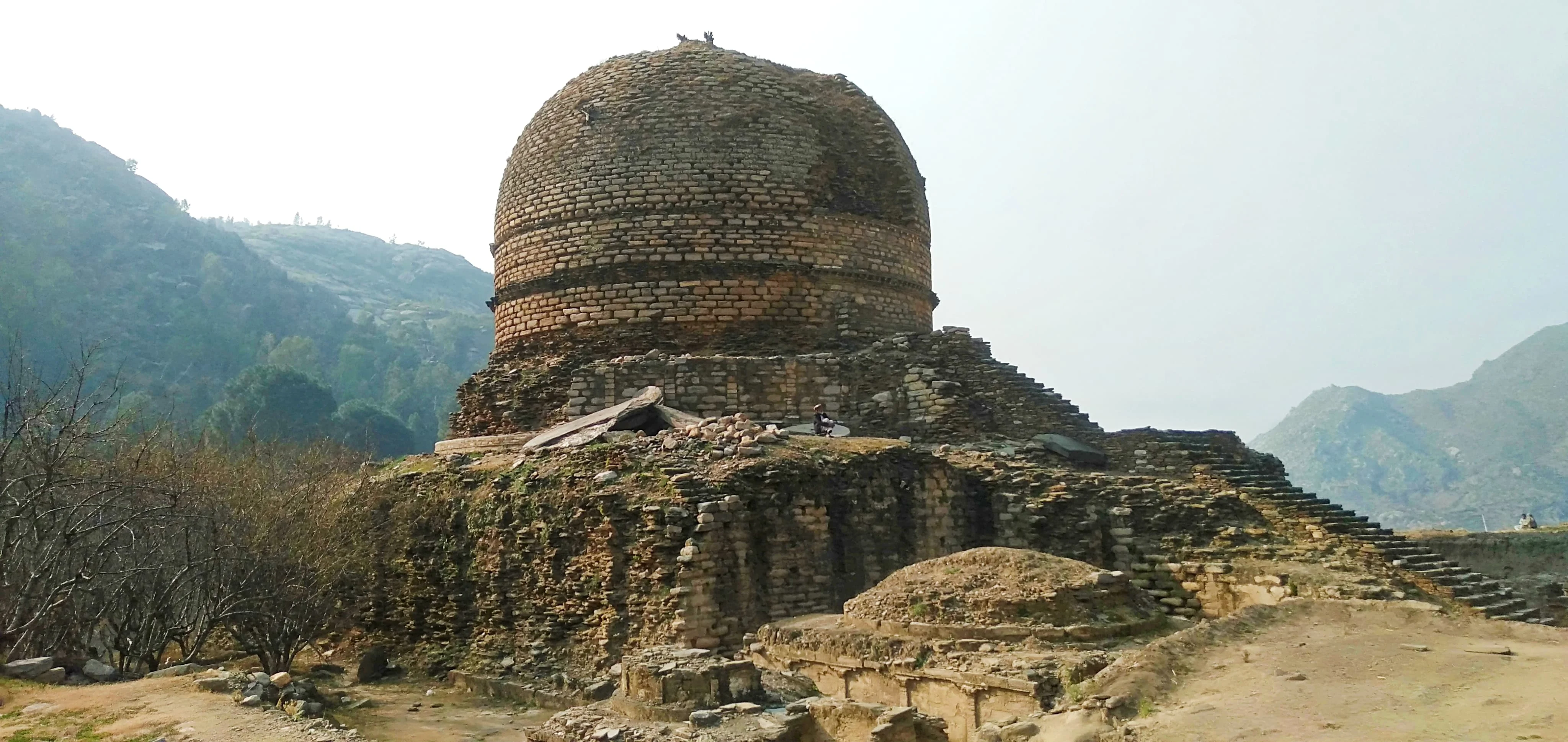 Amluk Dara Stupa in Swat Valley Pakistan, ancient Buddhist dome with mountains in background.