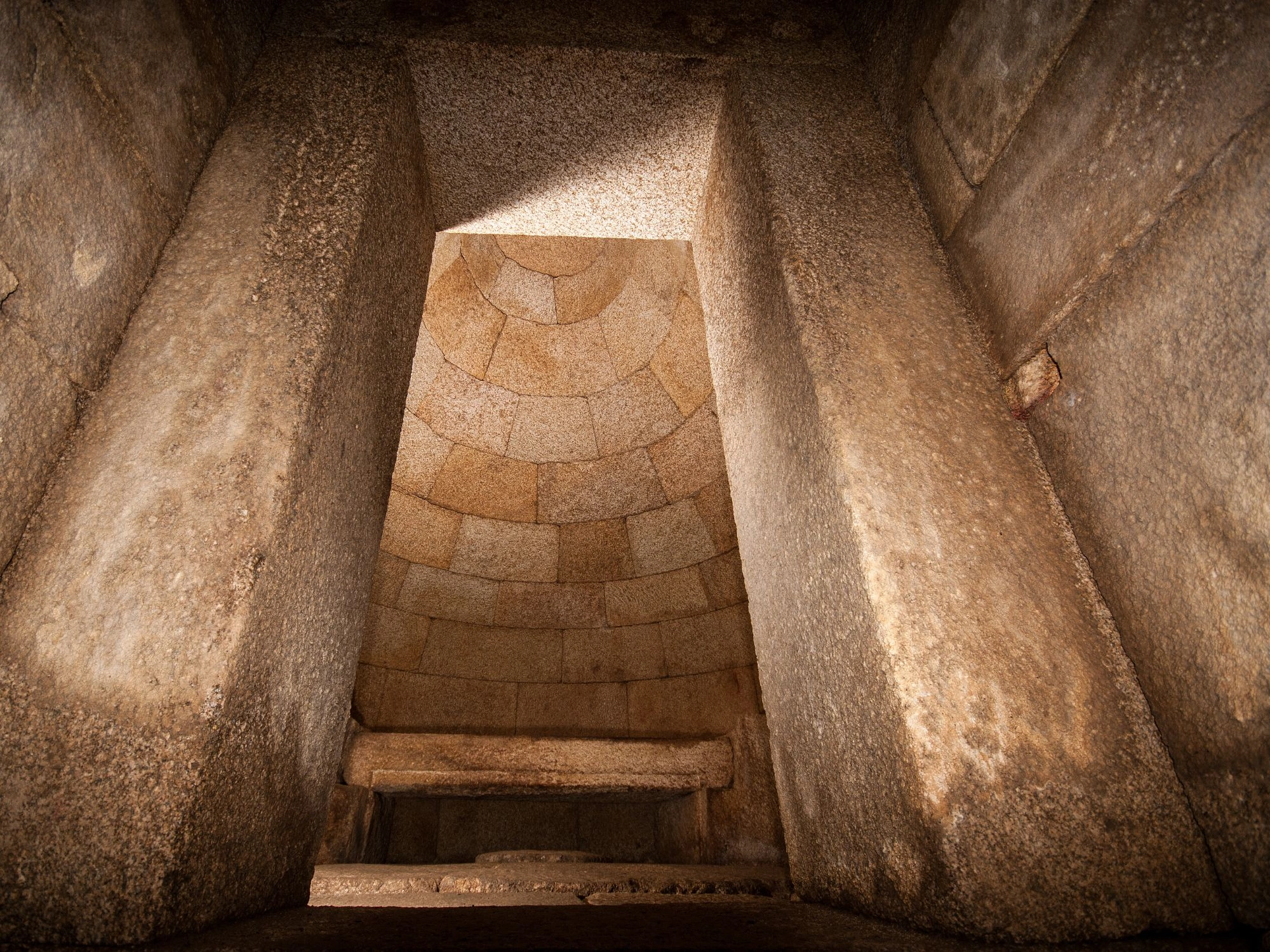 Interior of a stone-built ancient tomb chamber with corbelled dome ceiling.