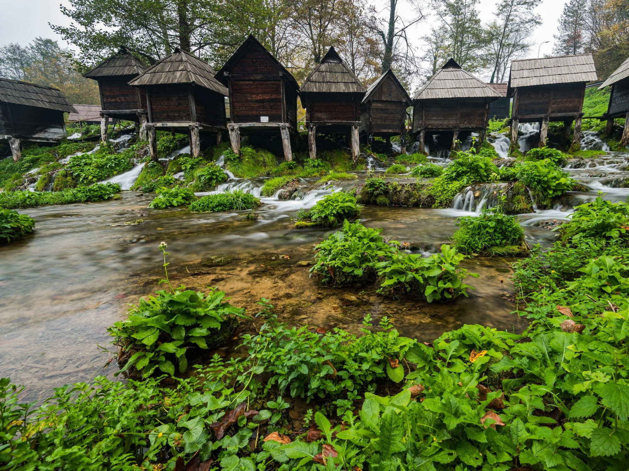Charming wooden watermills sitting atop a rushing stream in lush greenery at Jajce, Bosnia and Herzegovina.