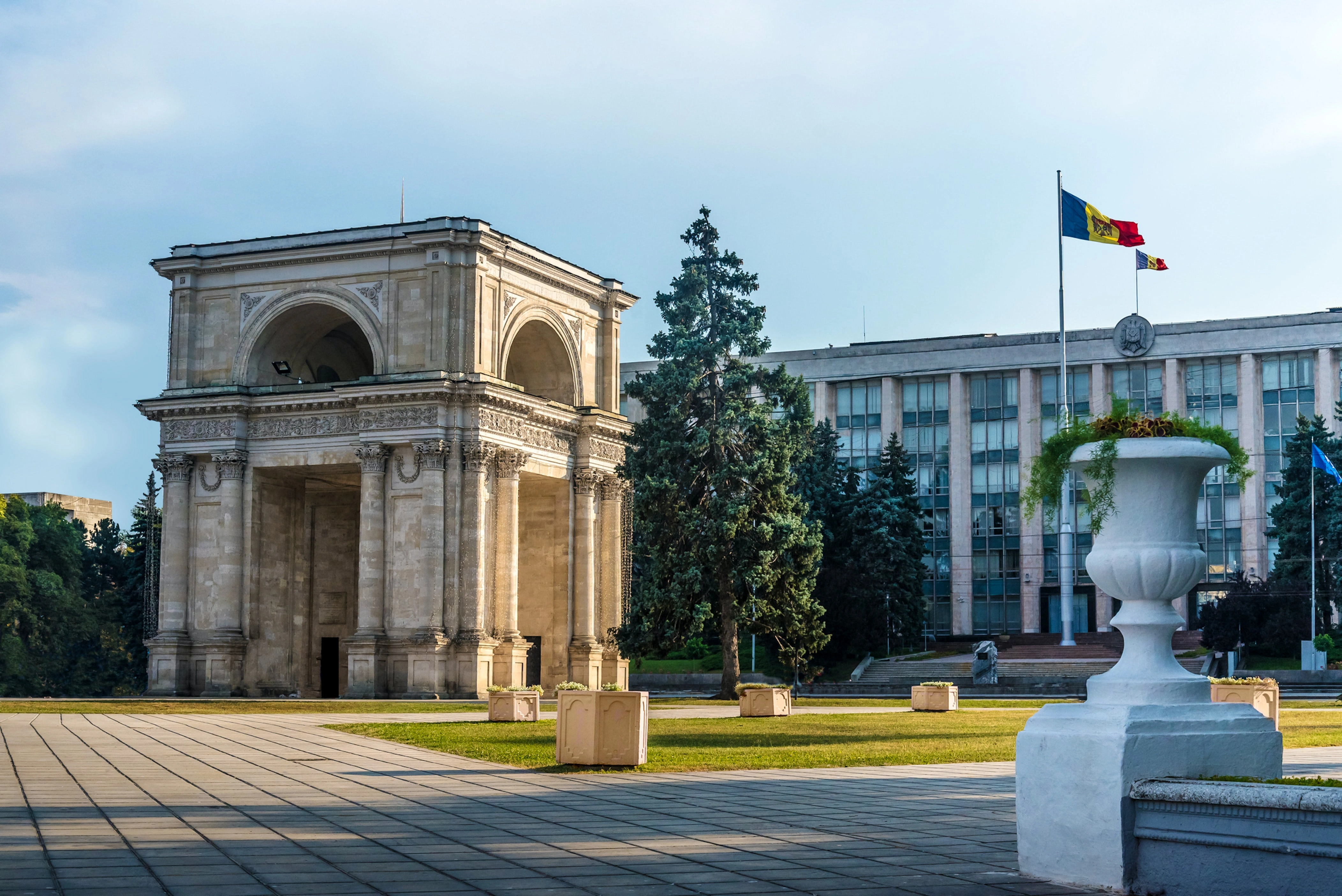 Chisinau Triumphal Arch with Moldovan flag and government building in the background.
