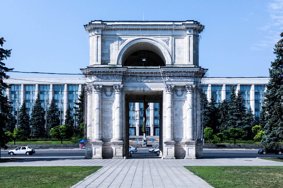 Front view of Chisinau’s Triumphal Arch with Moldovan Parliament building.