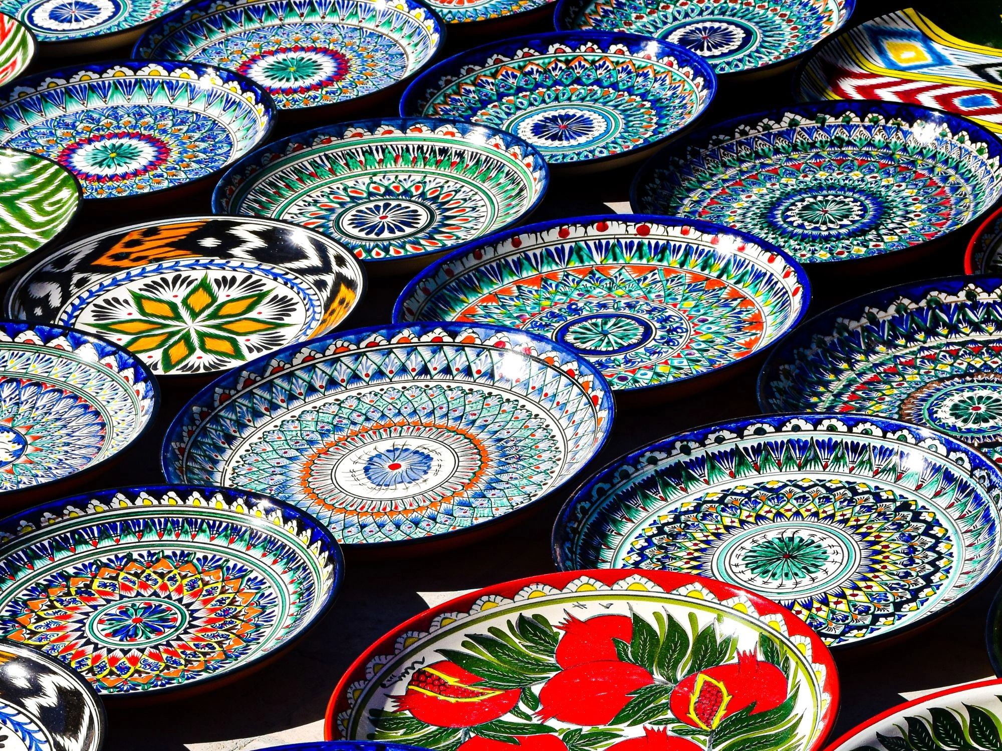 Vibrant hand-painted Uzbek ceramic plates with intricate geometric and floral patterns in Bukhara