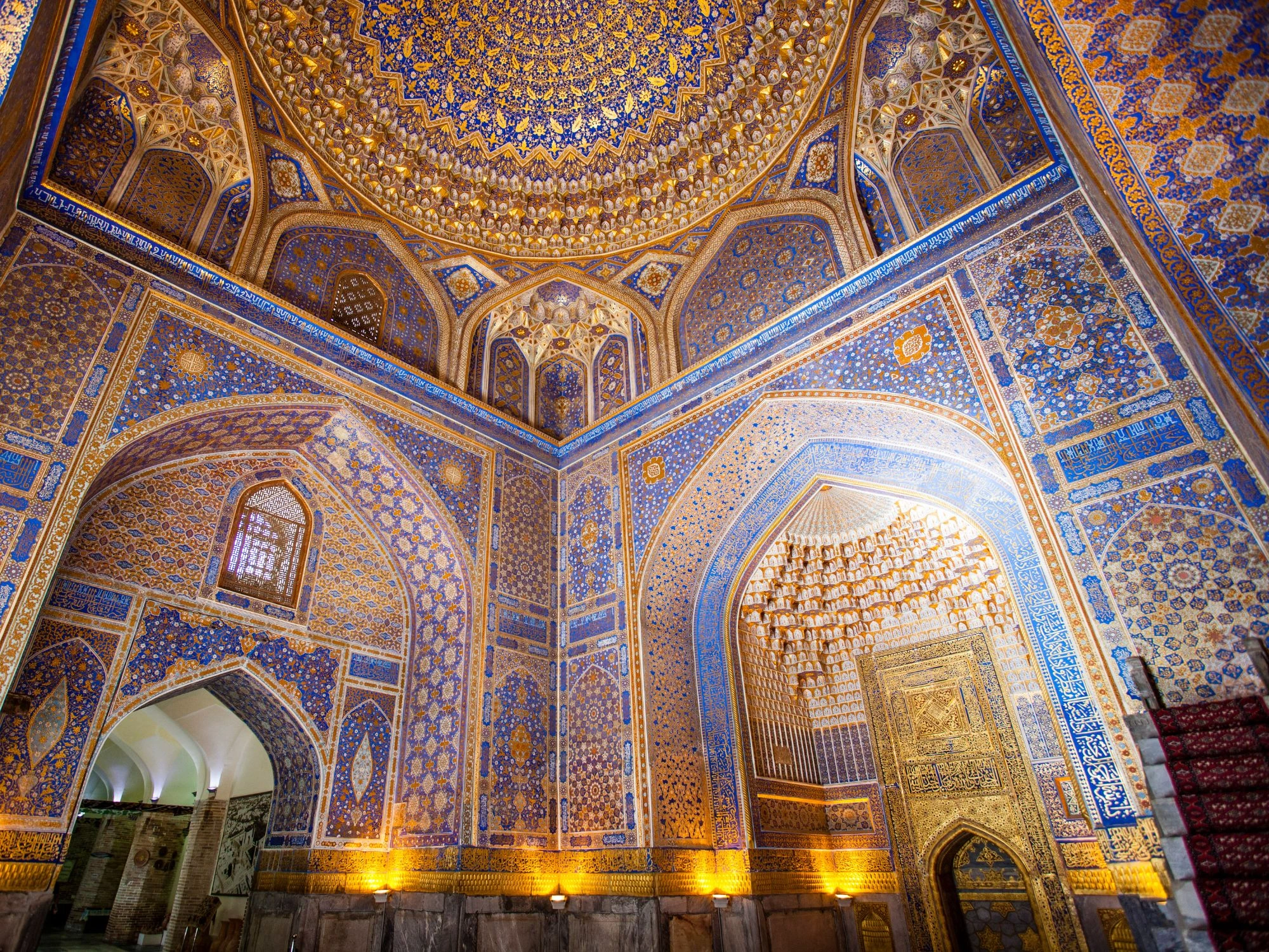 Ornate golden ceiling and intricate wall patterns inside the historic Tilla-Kari Madrasa at Registan Square in Samarkand, Uzbekistan.