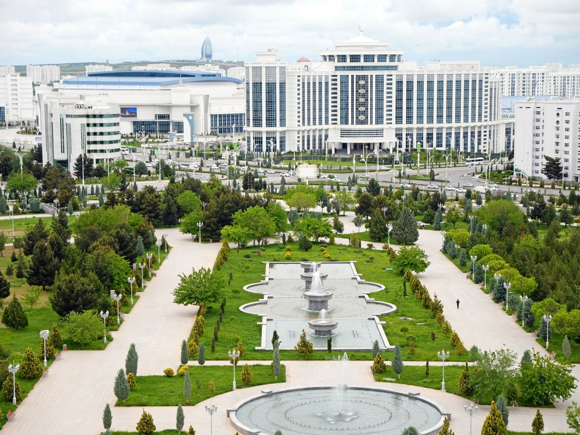 Public park in Ashgabat, Turkmenistan, with fountains and modern white buildings in the background.