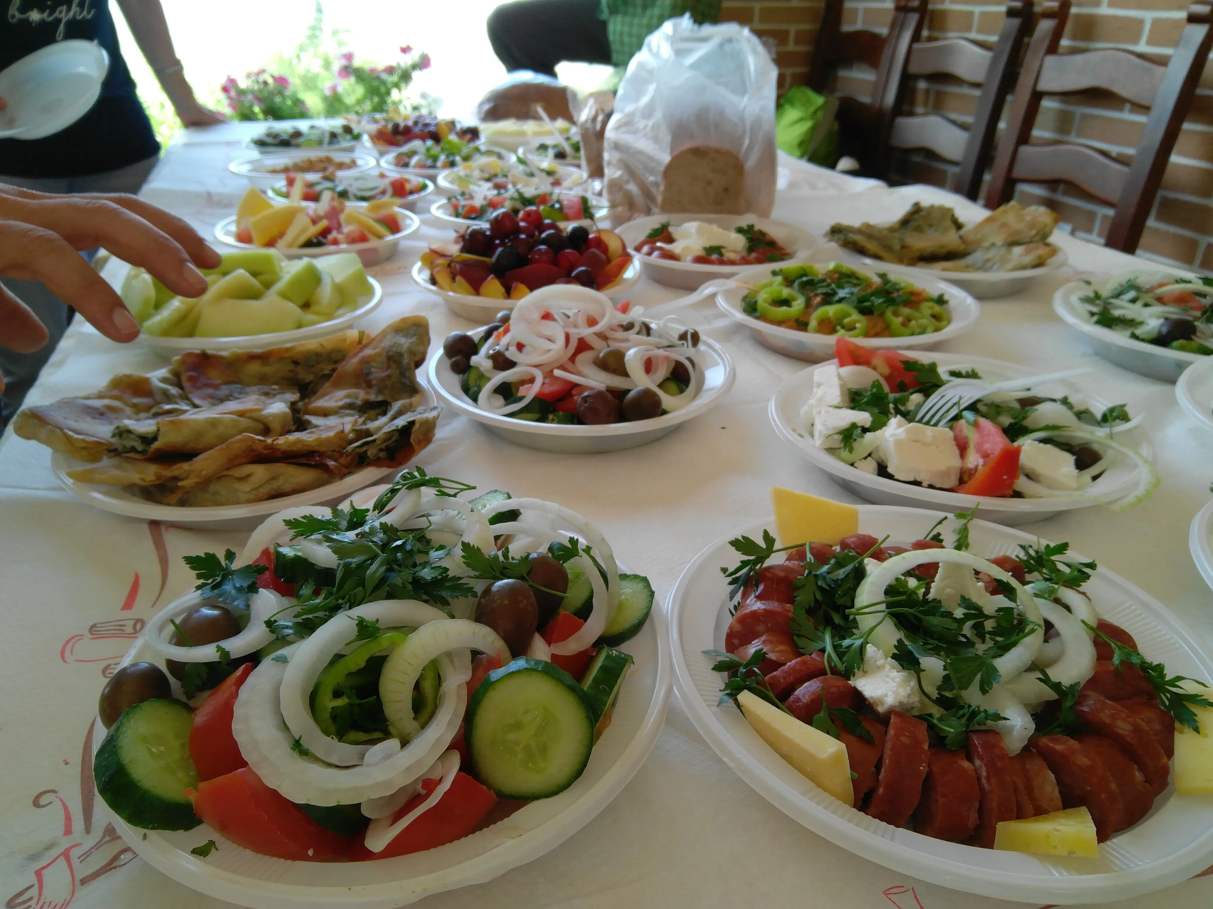 Assorted Balkan meze plates with salads, meats, cheese and fresh fruit laid out on table