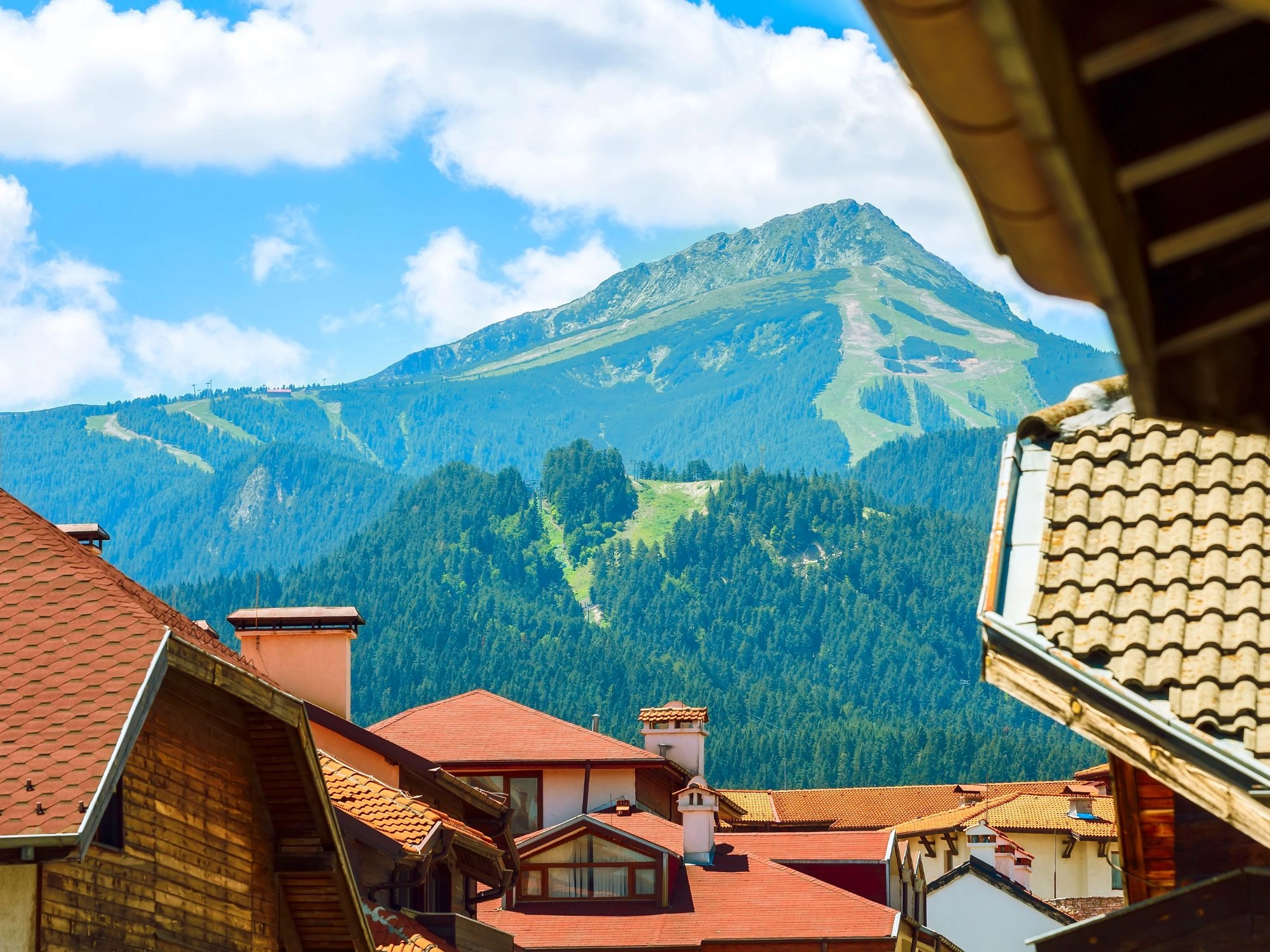 Bansko town rooftops with Pirin Mountain ski slopes in the background, a top Bulgarian winter destination.
