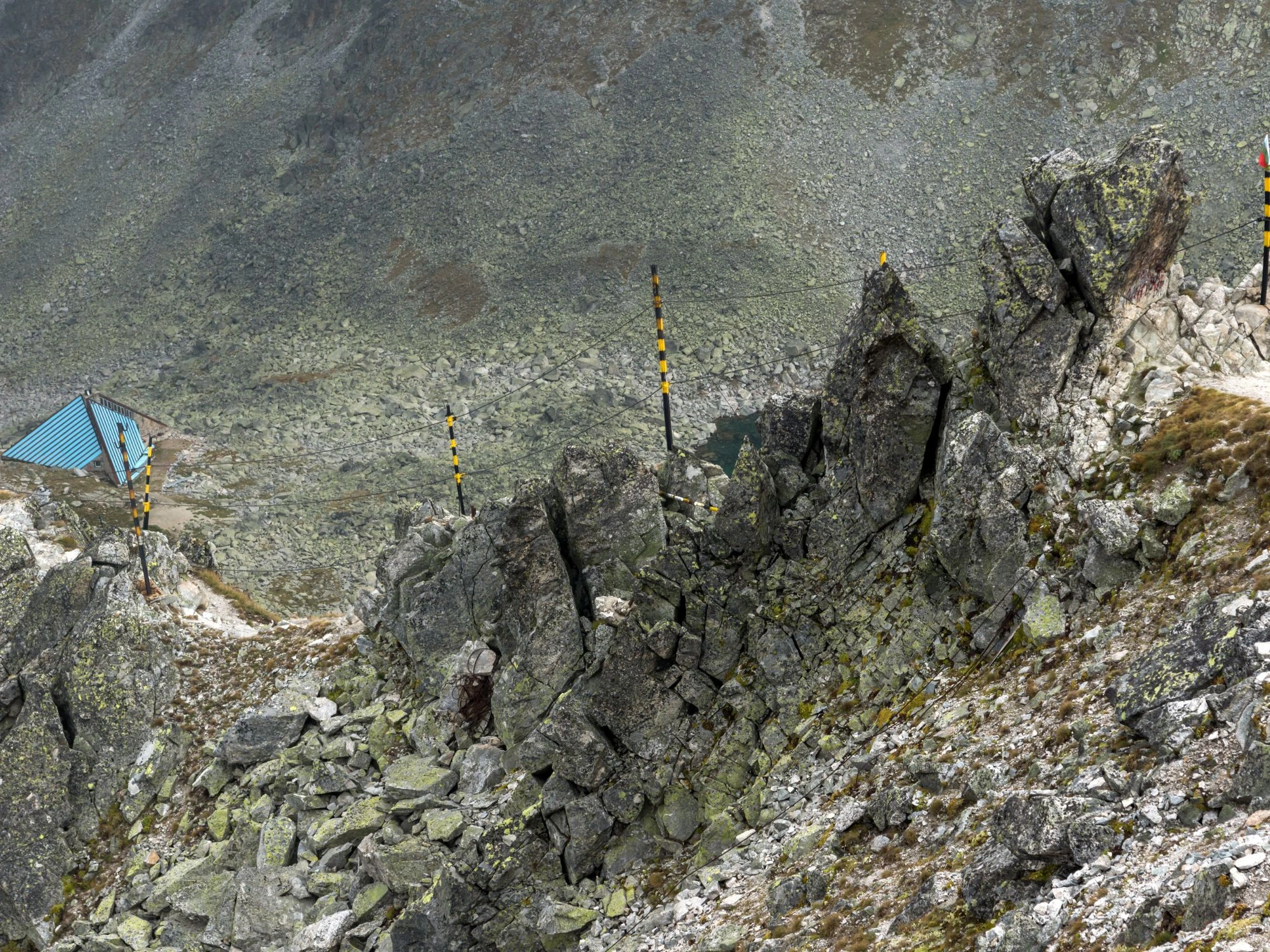 Jagged mountain peaks near the Rila Lakes, Bulgaria, with a Bulgarian flag marking a high-altitude trail.