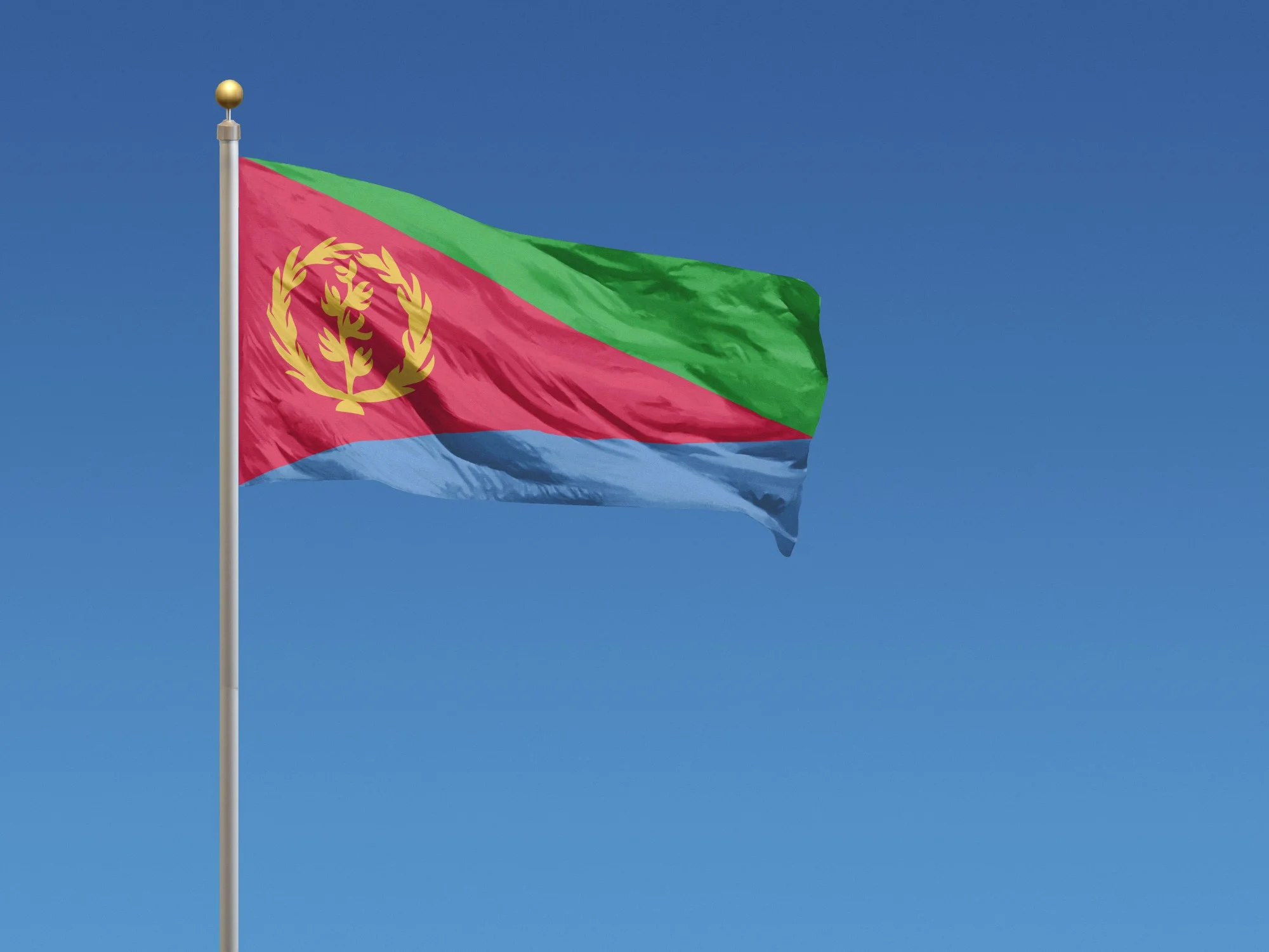Eritrean national flag waving on a flagpole against clear blue sky