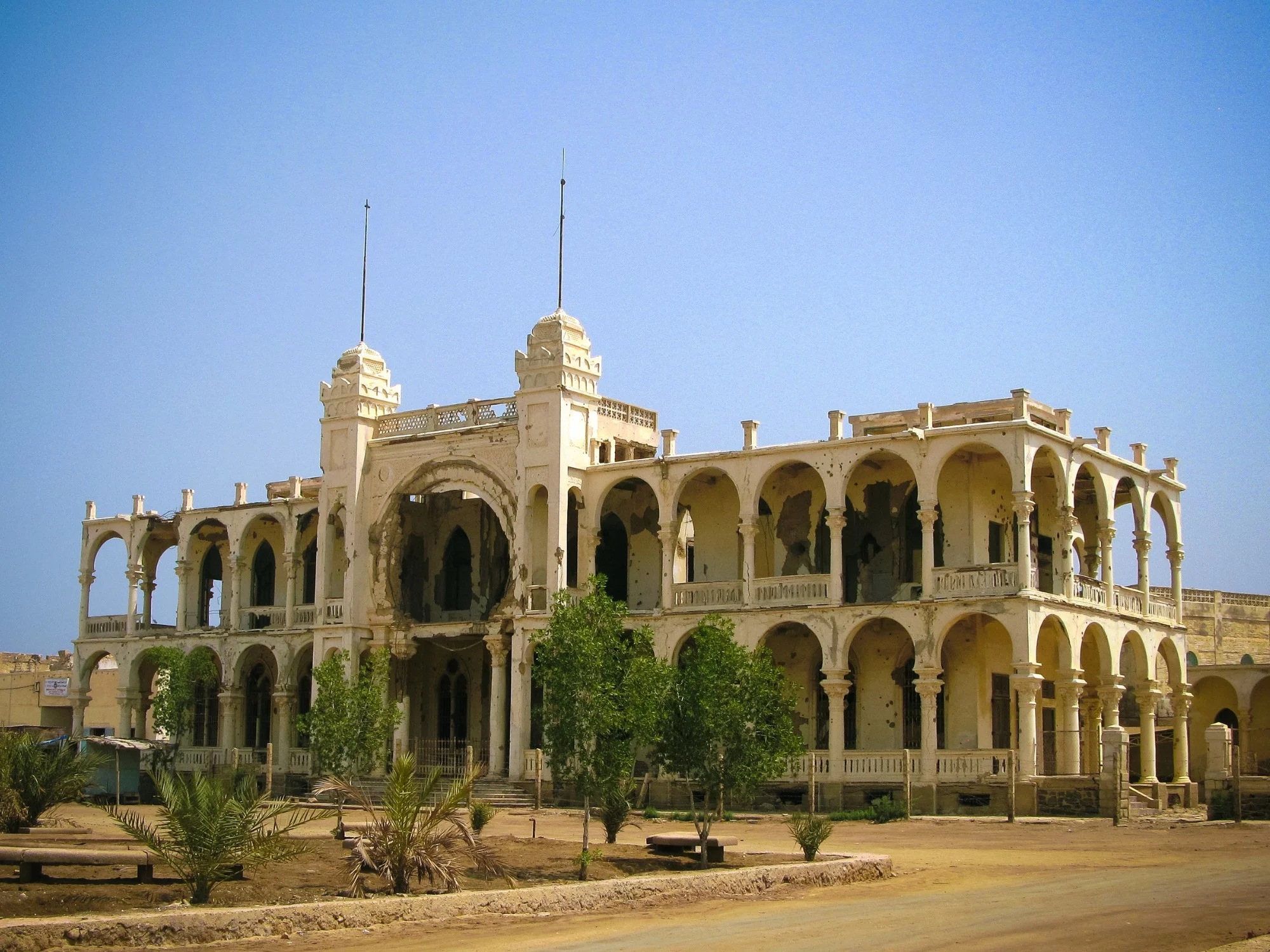 War-damaged colonial-era coral mansion with arches in Massawa, Eritrea under blue sky