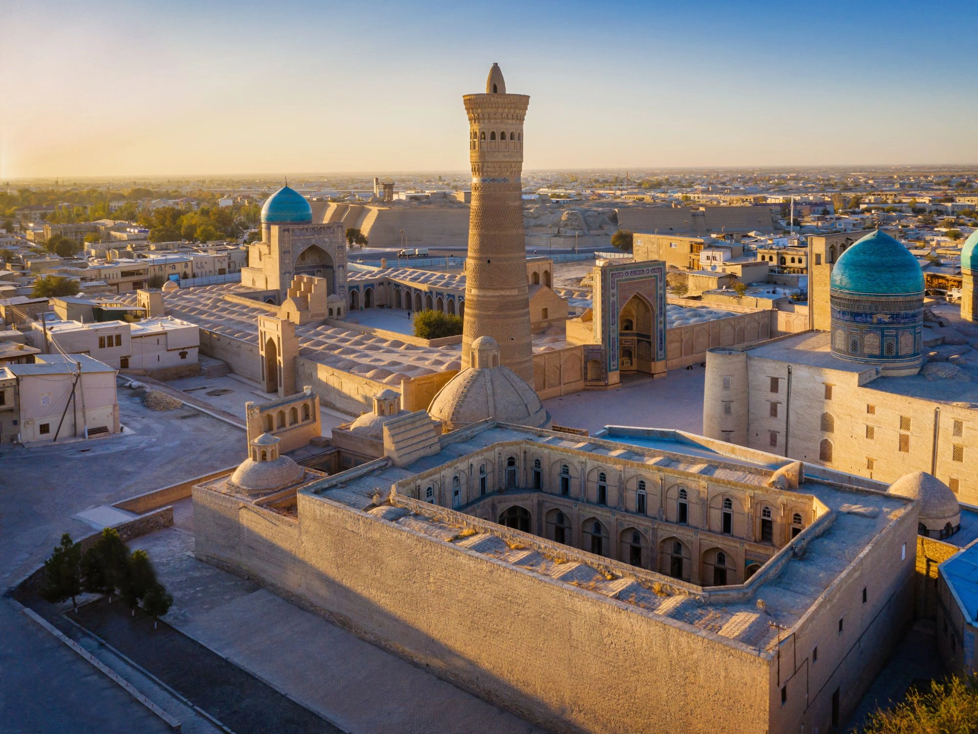 Sunset view over Bukhara’s historic Poi Kalon complex, featuring the iconic Kalon Minaret and Mir Arab Madrasah, highlights of Uzbekistan’s Silk Road heritage.
