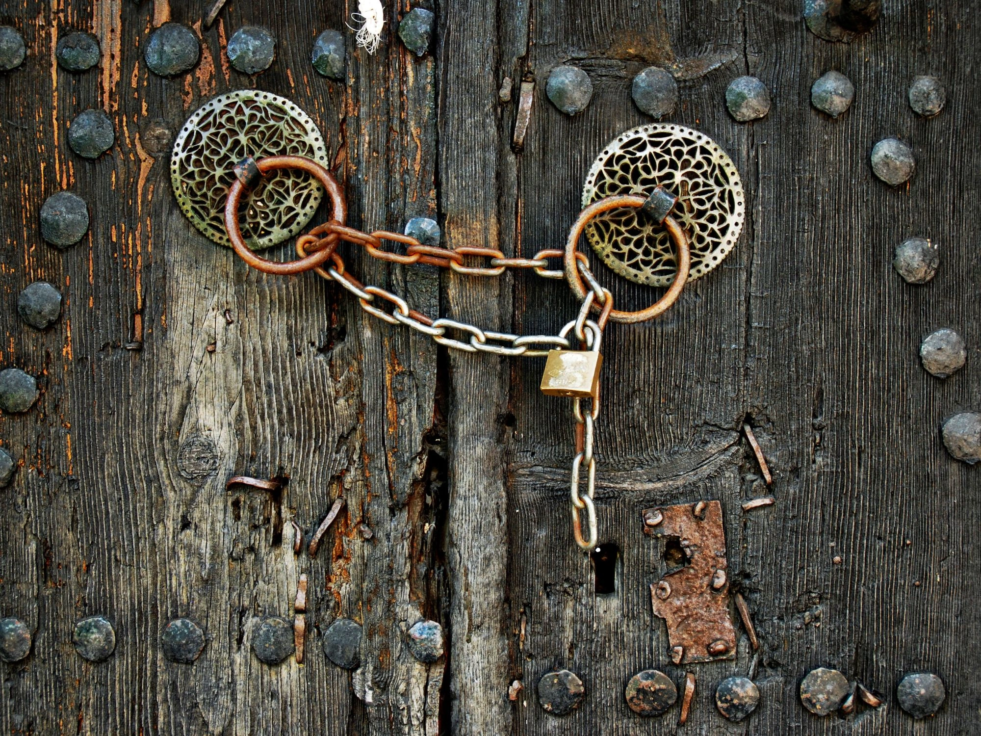 Close-up of an old wooden door with metal rings and a rusty chain lock, Monodendri village, Epirus, Greece travel.