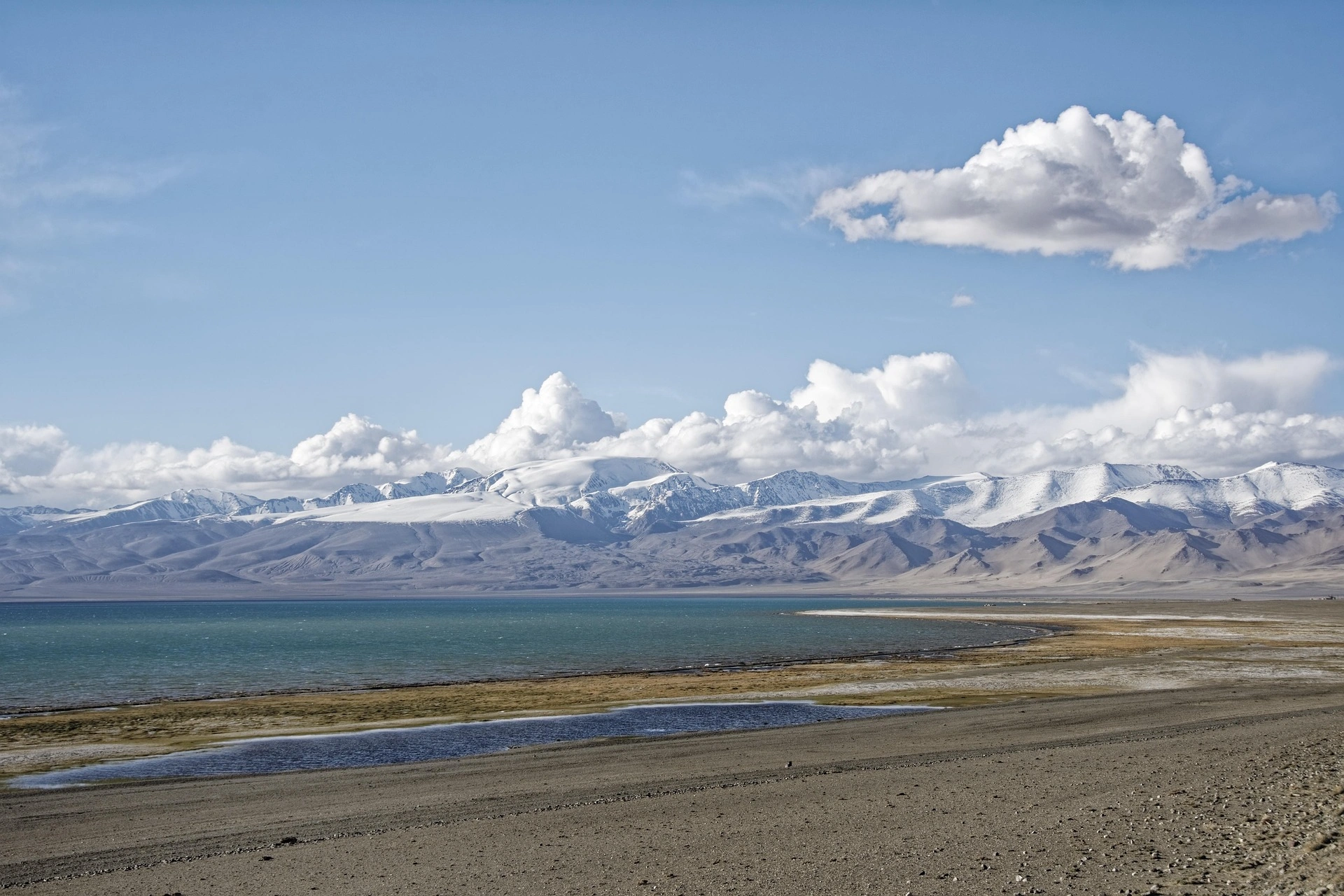 Snow-capped peaks rise over green valleys in the Pamir Mountains near the Tajikistan-Afghan border.
