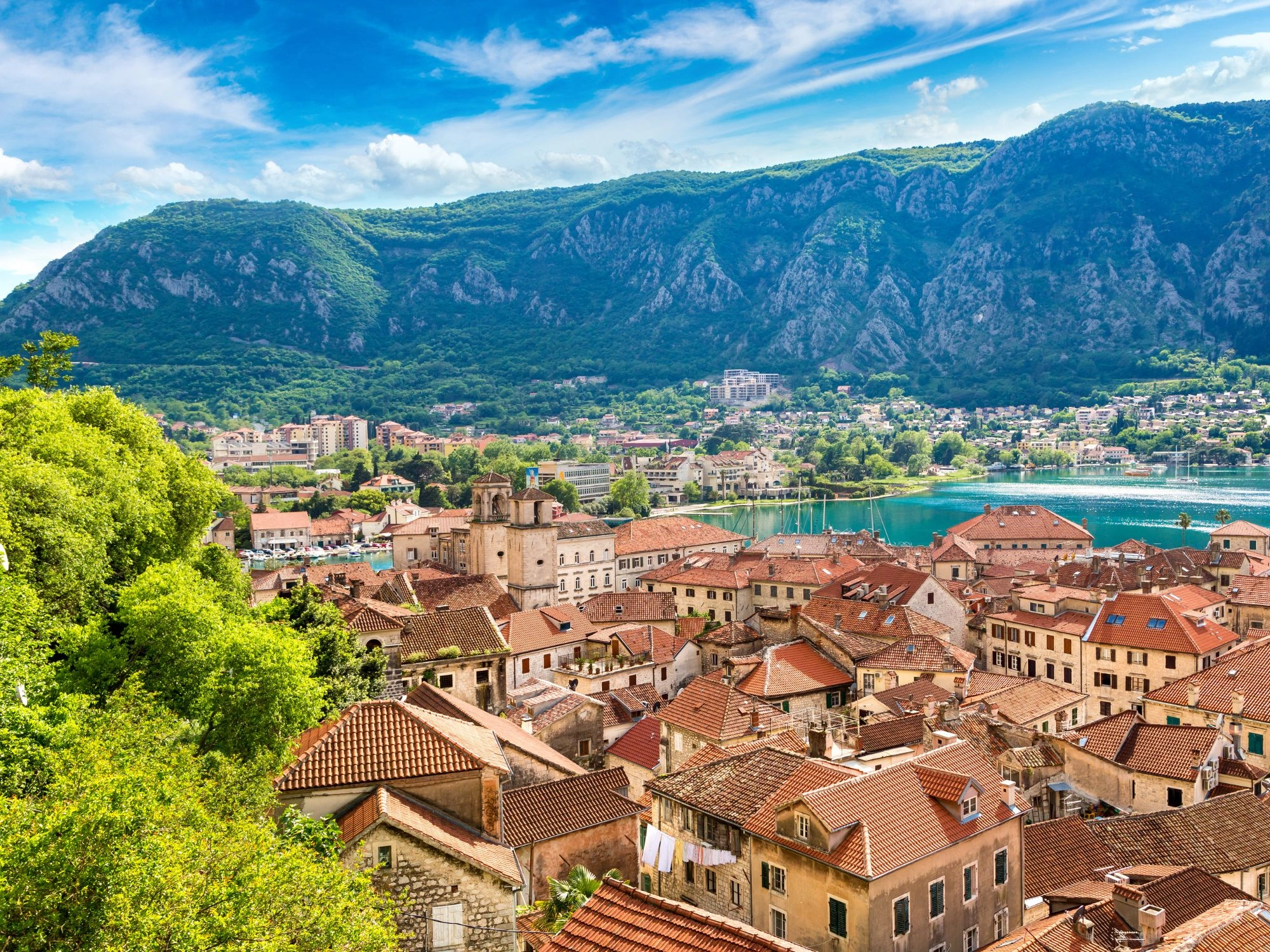 Scenic rooftops of Kotor, Montenegro with dramatic mountains and bay in the background.