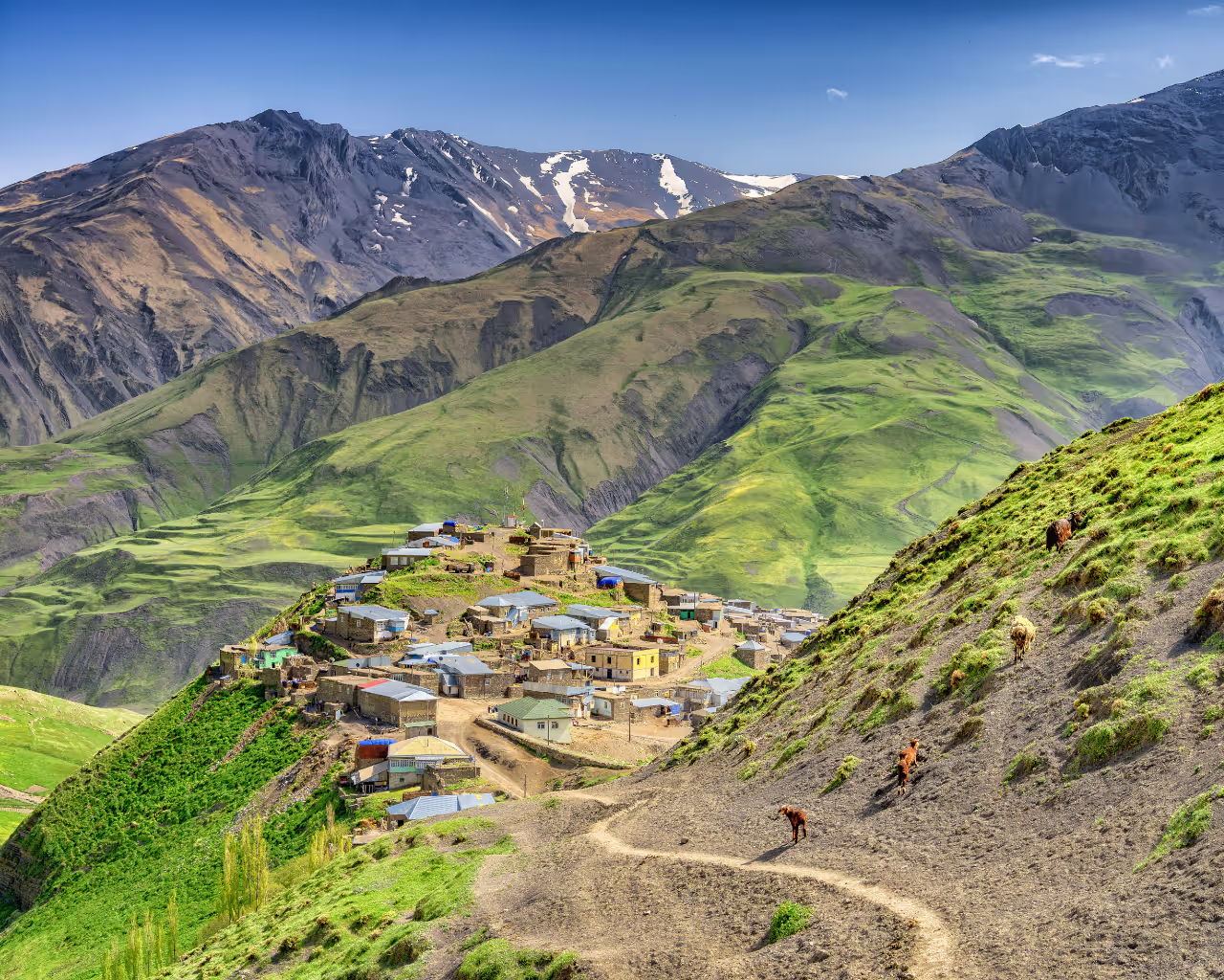 Aerial view of Khinaliq, Azerbaijan, a remote mountain village surrounded by rolling green hills and rugged landscapes.