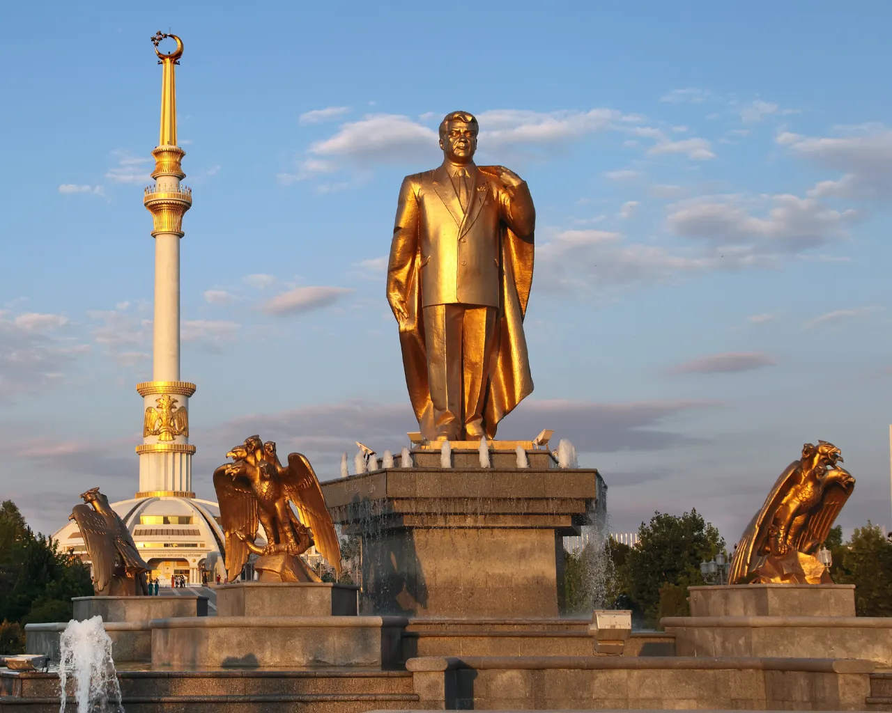 Golden statues of Niyazov and the Independence Arch glowing in Ashgabat, Turkmenistan.