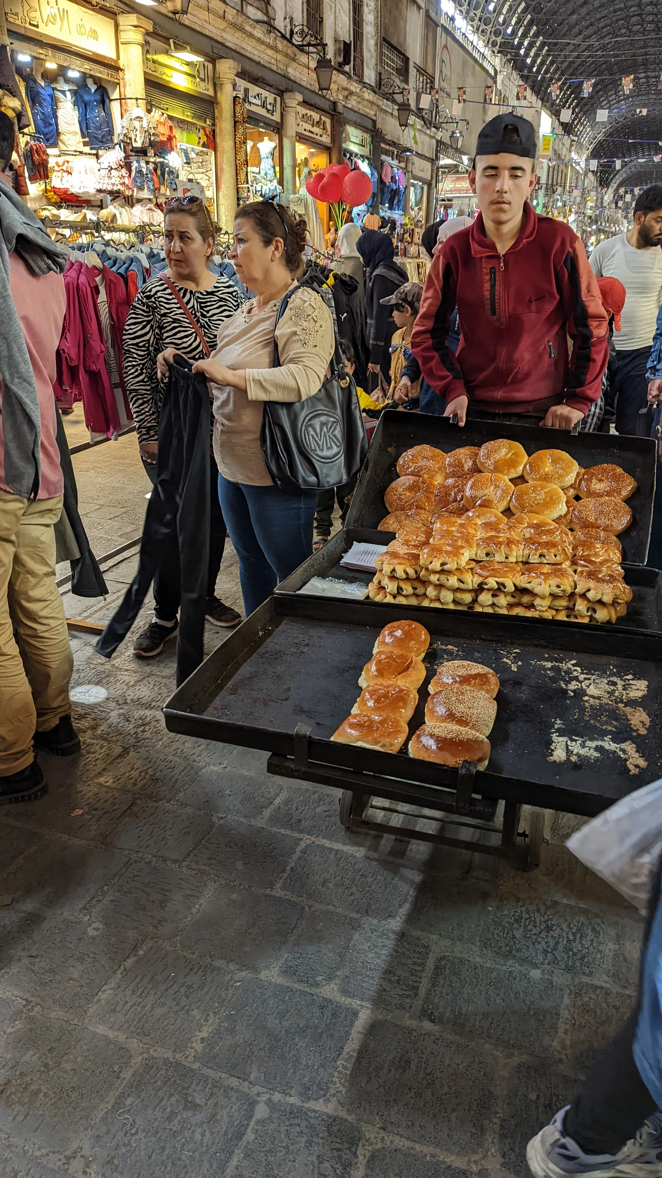 Street vendor selling fresh sesame bread rolls at Al-Hamidiyah Souq in Damascus