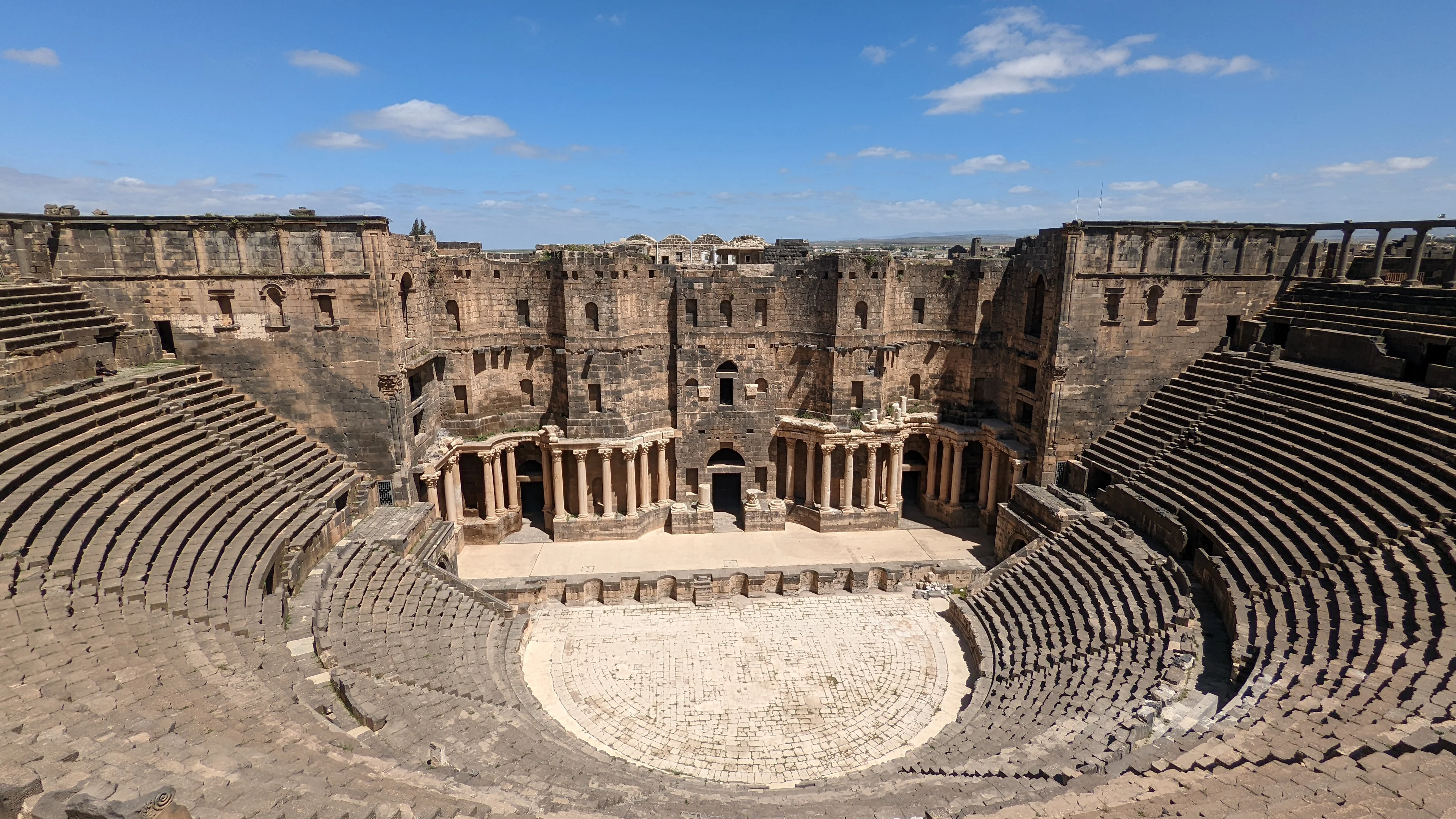 Ancient Roman amphitheater in Bosra with preserved stone seating and central performance stage