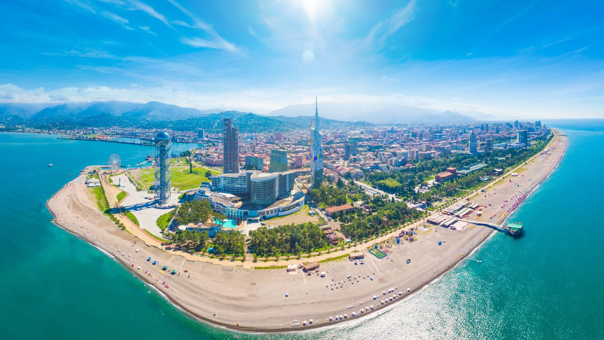 Aerial panoramic view of Batumi, Georgia with Alphabet Tower, Ferris wheel, modern skyscrapers, and Black Sea coastline