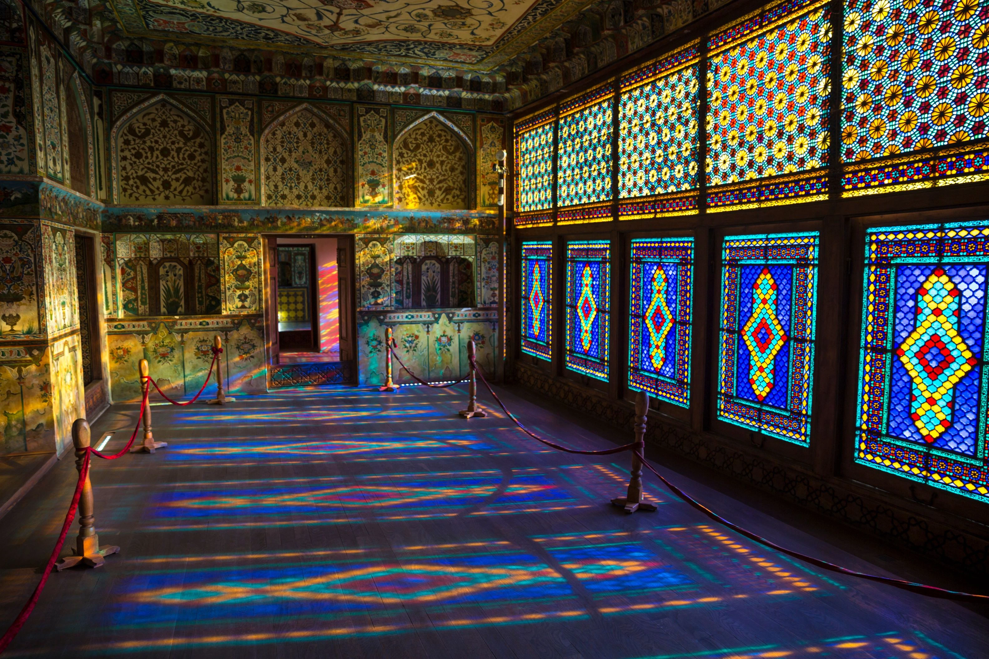 Interior of Sheki Khan’s Palace in Azerbaijan with colorful stained glass windows and ornate floral wall paintings