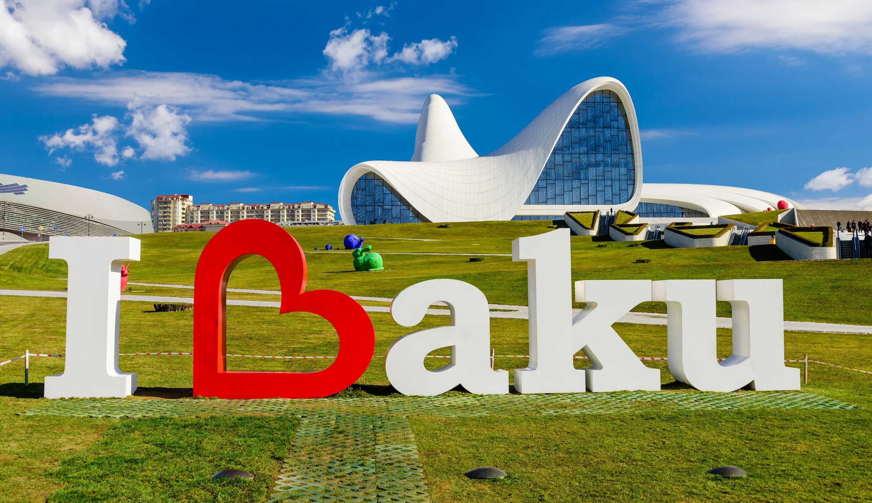 I Love Baku – large “I Love Baku” sign on green grass in front of the futuristic Heydar Aliyev Center in Azerbaijan.