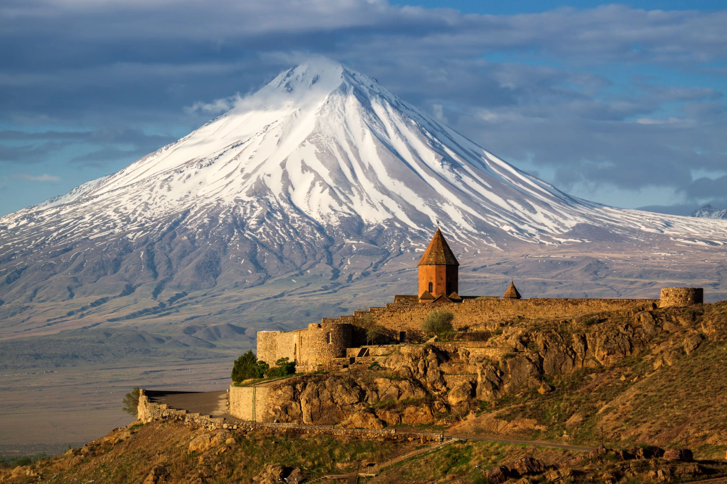 Caucasus Explorer tour – snow‑capped Mount Ararat towering over the hilltop Khor Virap monastery in Armenia’s Ararat Valley.