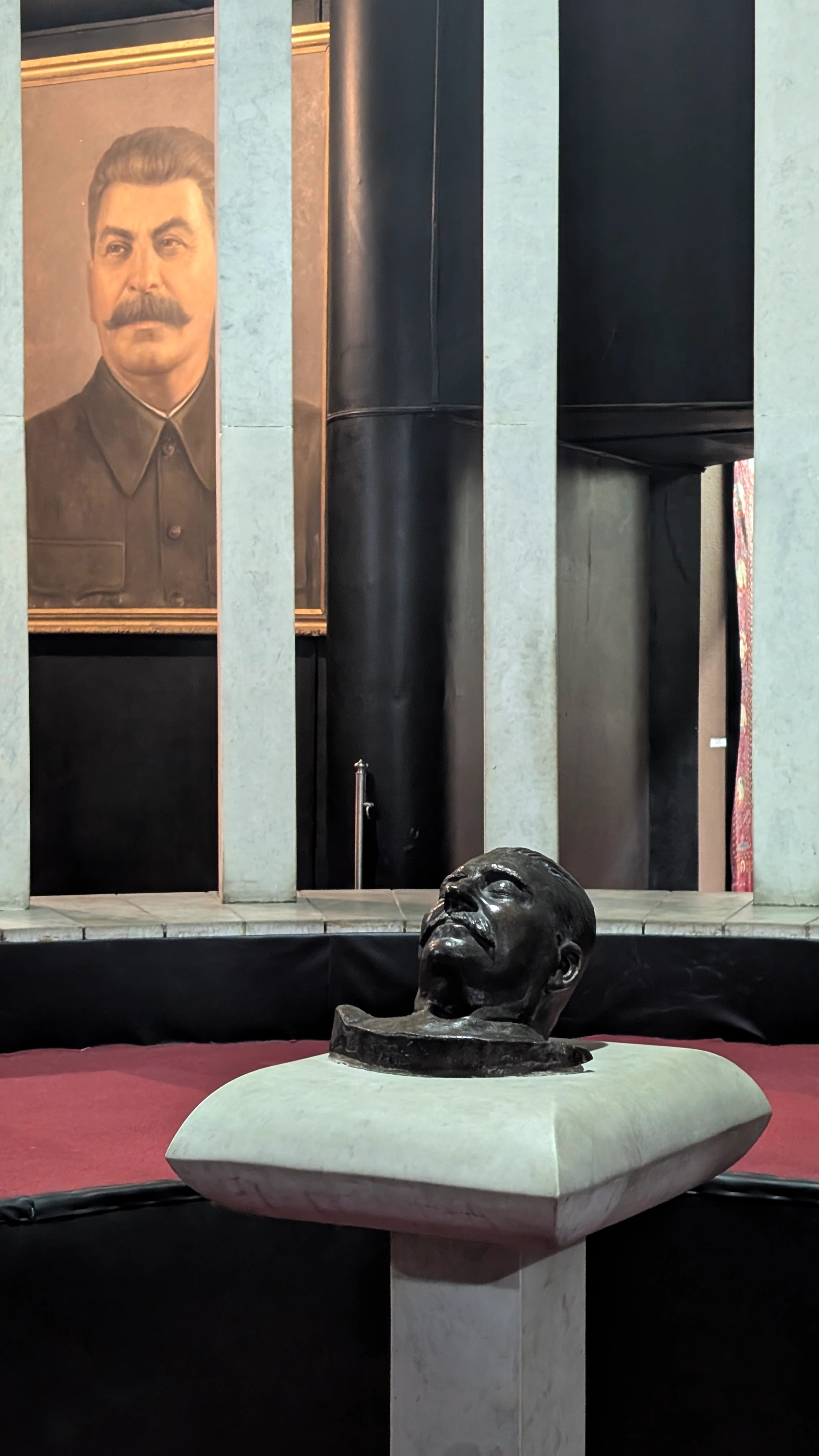 Joseph Stalin Museum – bronze bust of Joseph Stalin on a marble pedestal with a large portrait of Stalin behind in Gori, Georgia.