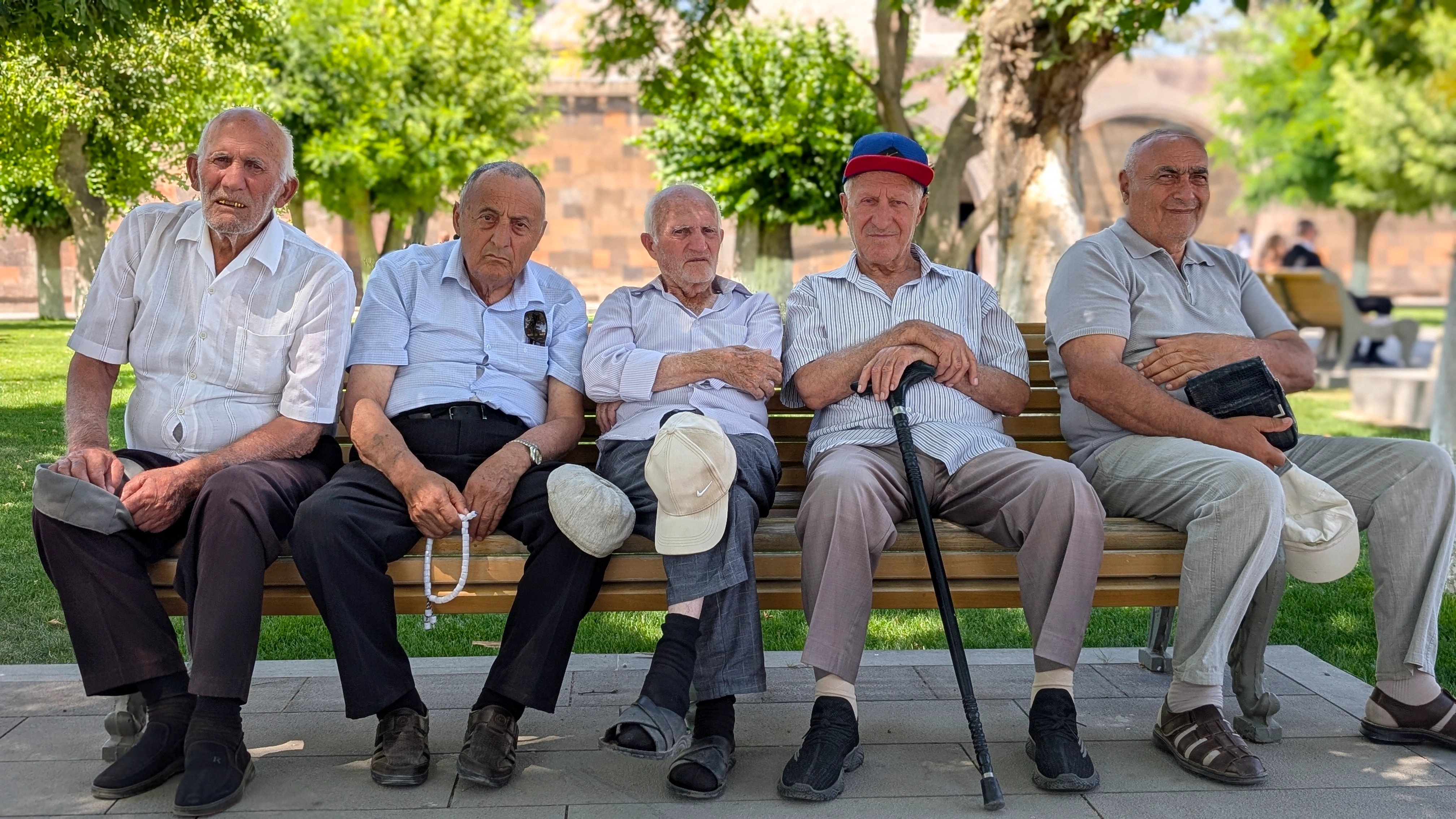 Elderly Armenian men – five elderly men in shirts and caps relaxing on a bench in a shaded park on a sunny day in Armenia.
