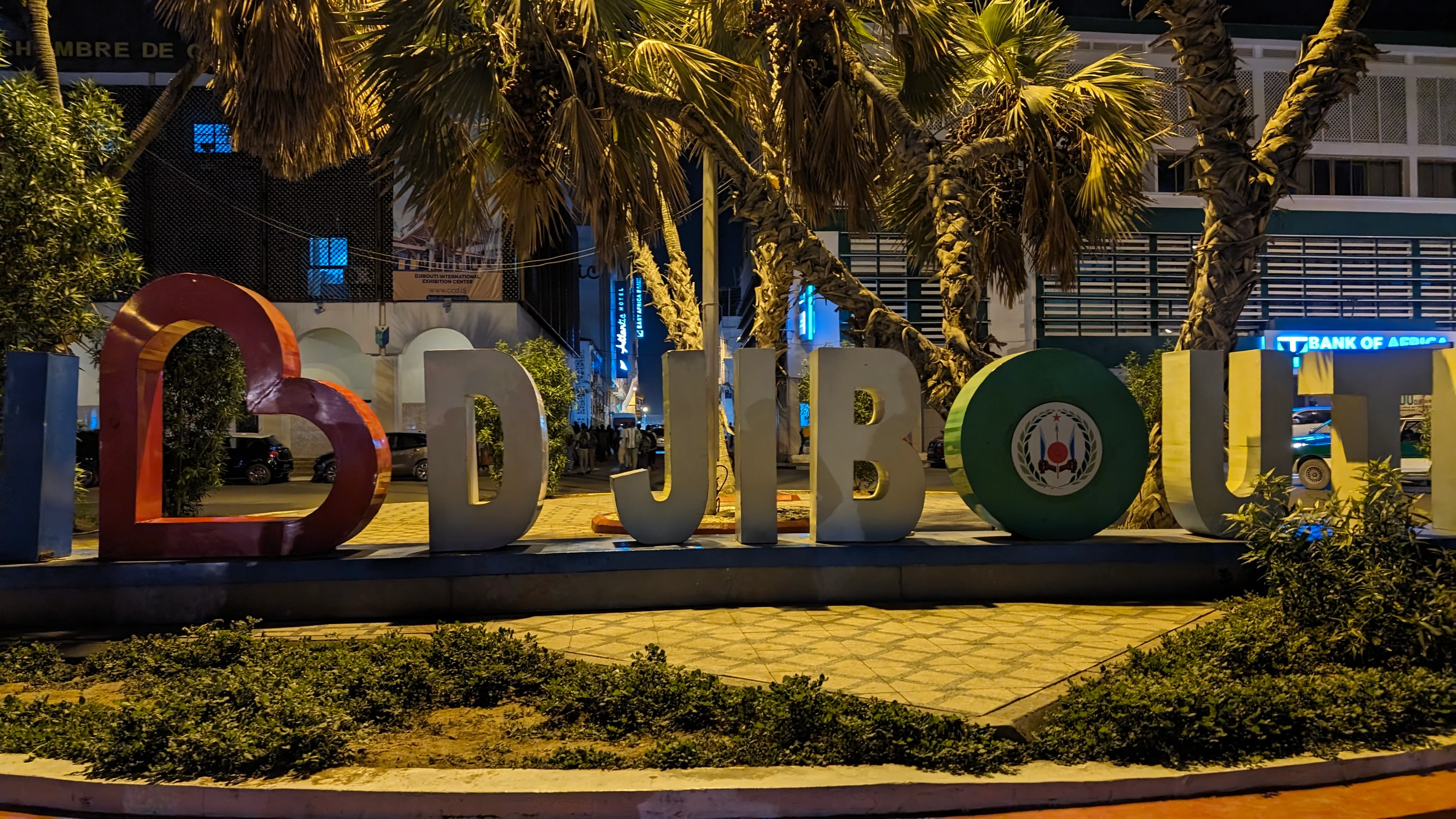 "I LOVE DJIBOUTI" sign lit up at night with palm trees in the background in Djibouti City.