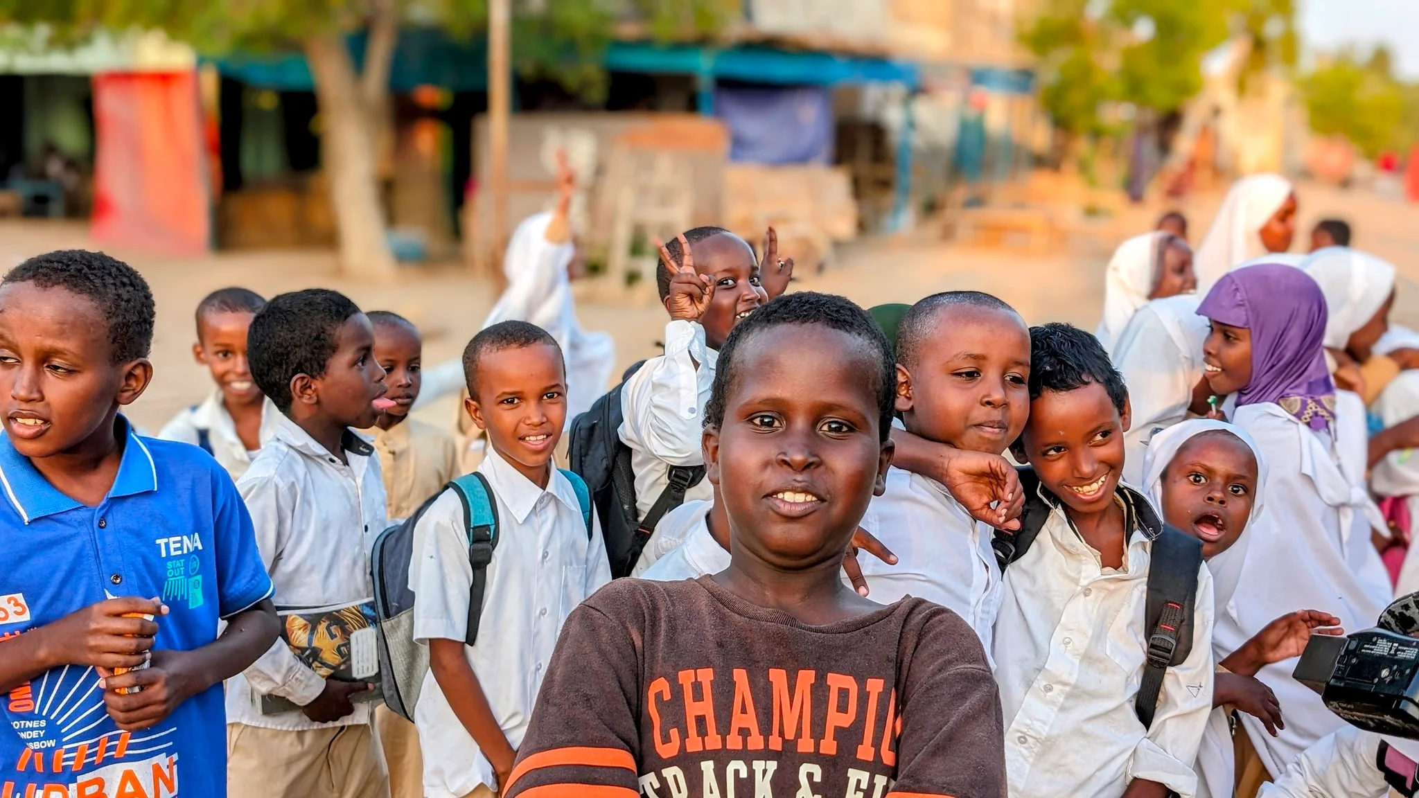 Smiling Somaliland schoolchildren pose together on a village street.