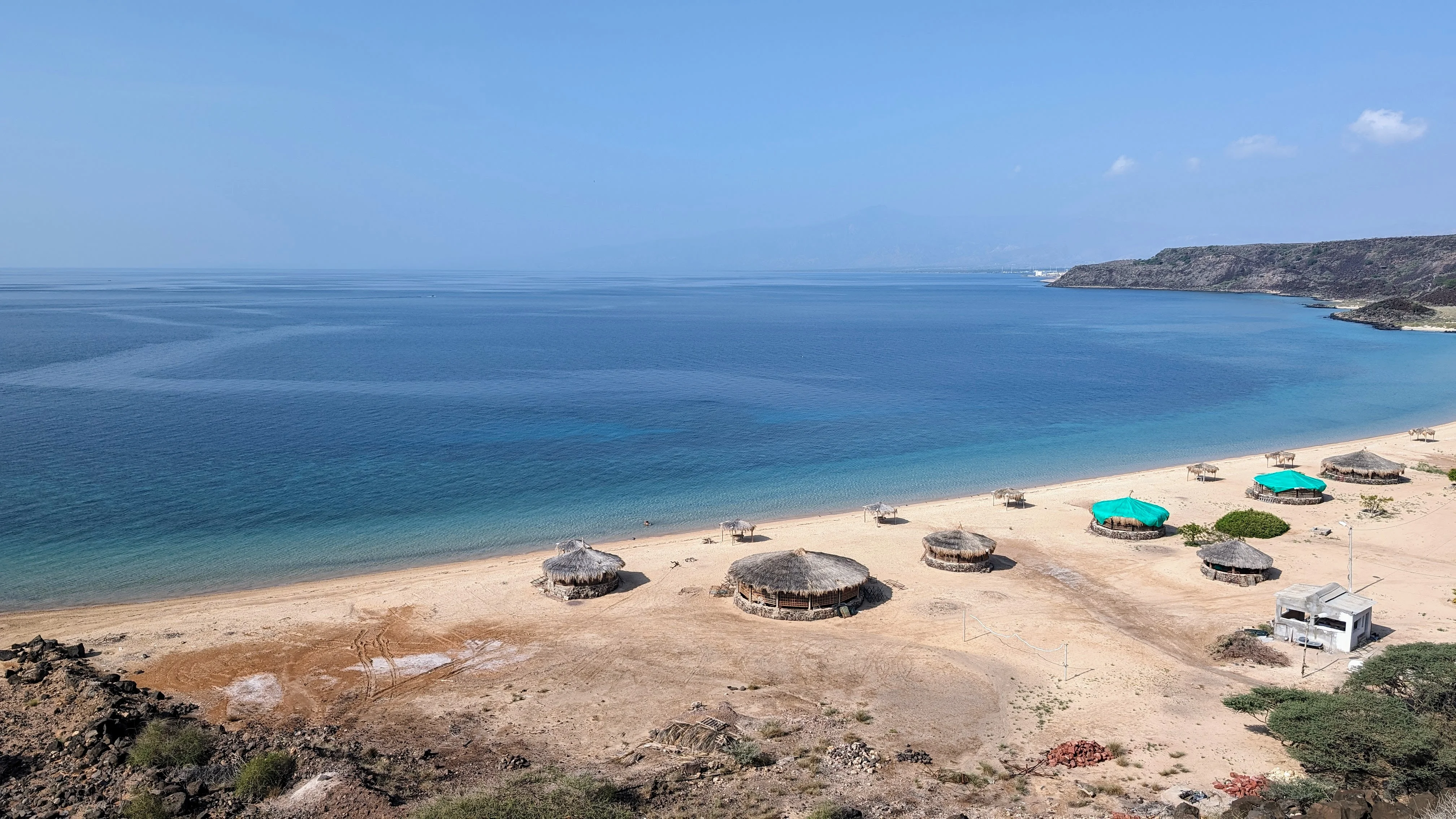 Quiet sandy beach with round thatched huts and turquoise Gulf of Aden waters in Somaliland.